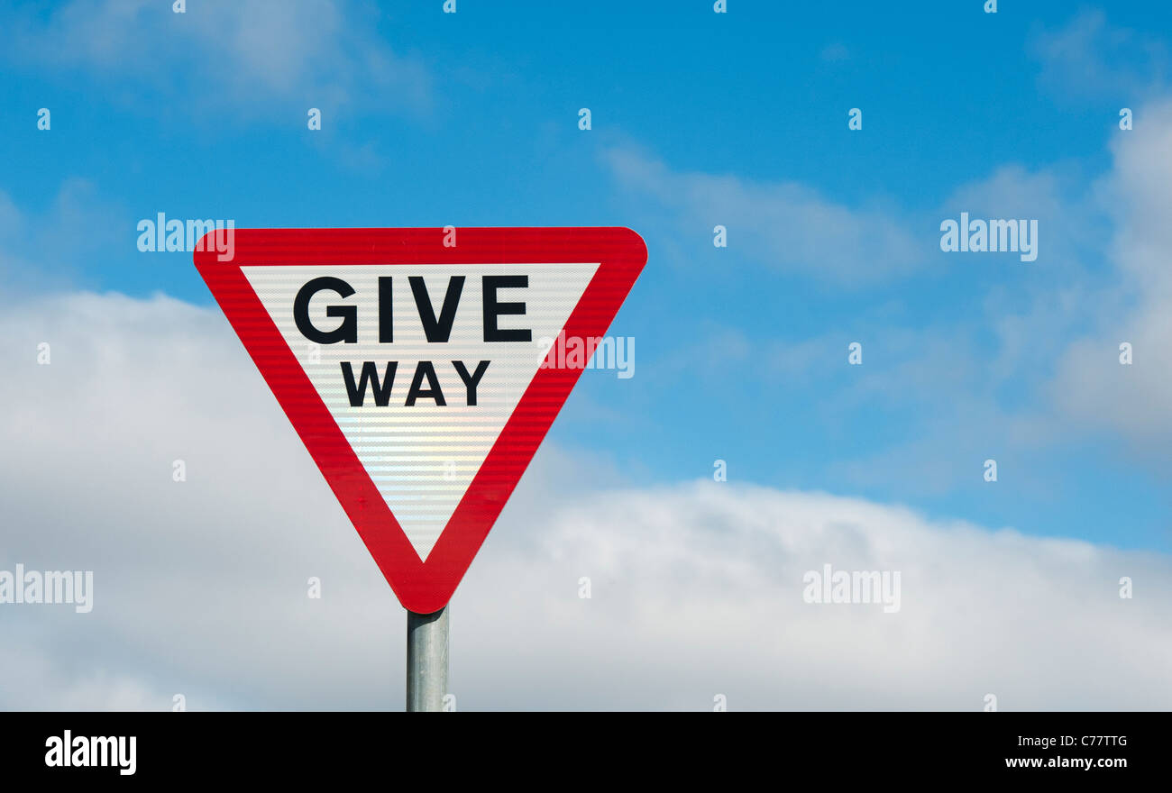 Give way warning road sign against blue cloudy sky. England Stock Photo