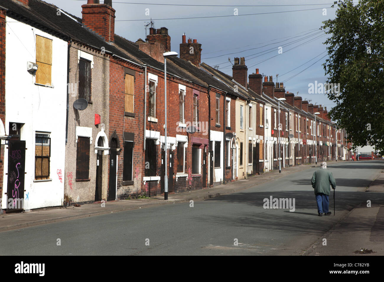 Middleport area of Stoke-on-Trent which vacated and boarded up An elderley man walks past boarded houses on Travers Street. Stock Photo