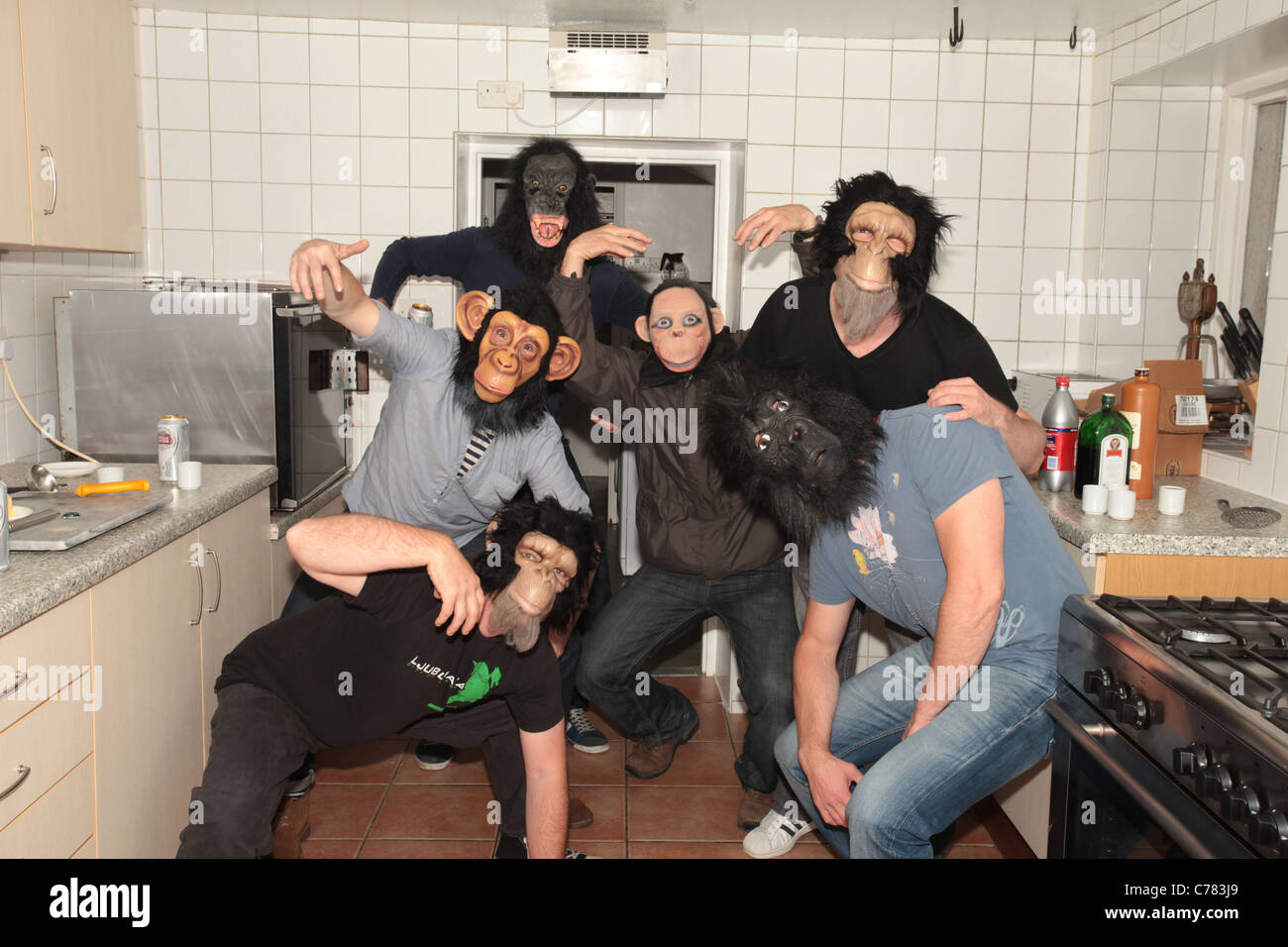 men wearing monkey masks in kitchen Stock Photo