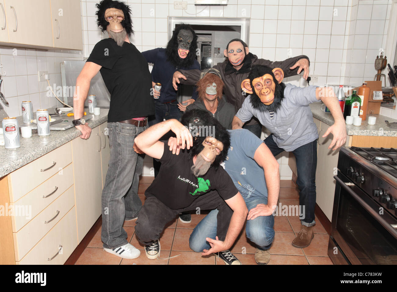 men wearing monkey masks in kitchen Stock Photo