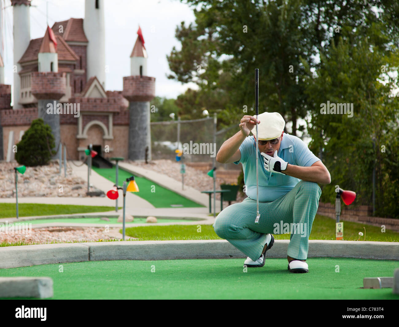 USA, Utah, Orem, Man lining up shot on miniature golf course Stock Photo