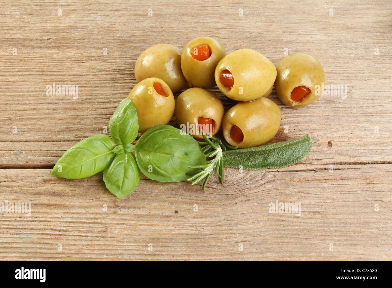 Olives and fresh herbs, basil, rosemary and sage on old weathered and cracked wood Stock Photo