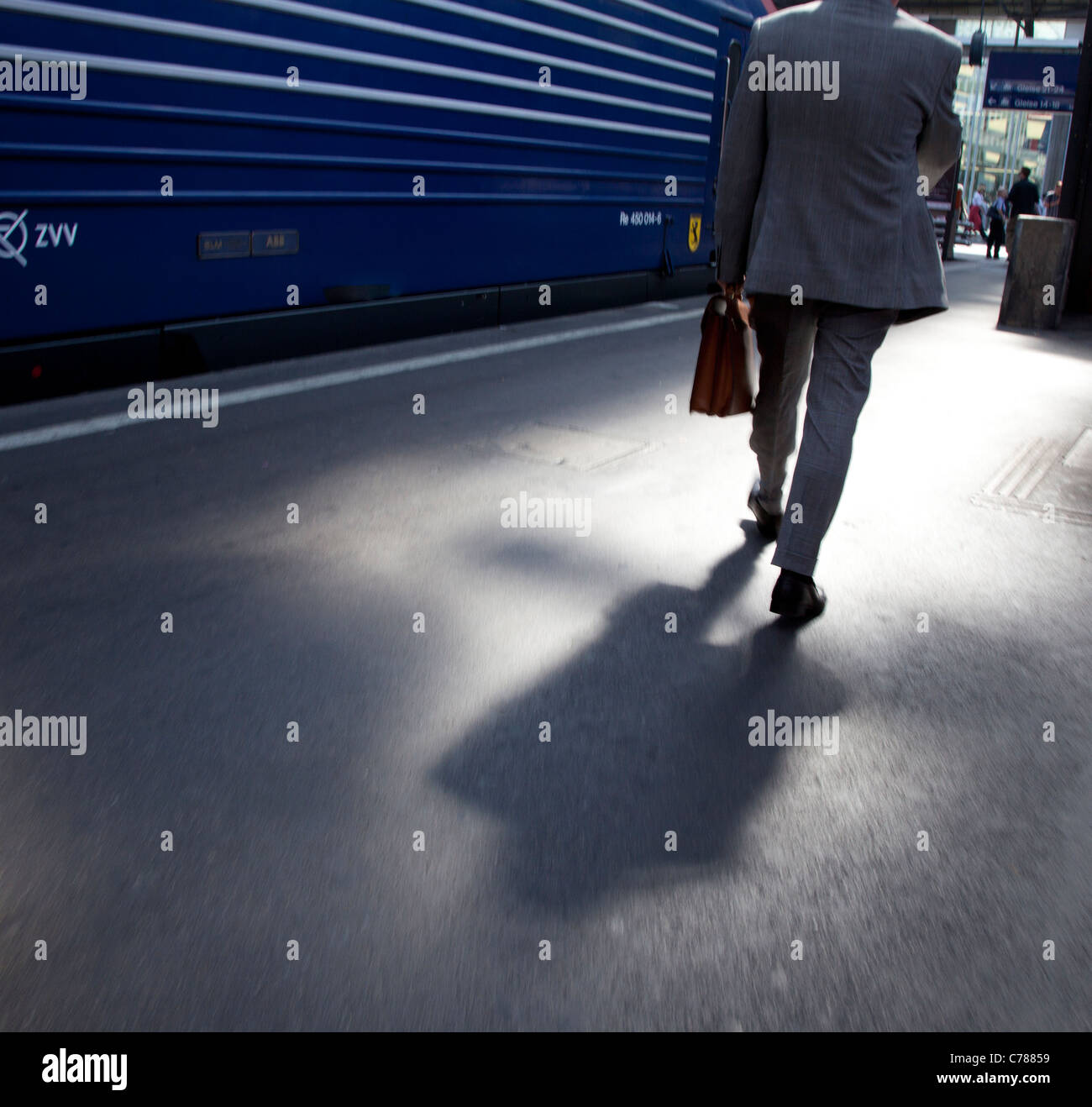business man walking in train station with briefcase back light Stock Photo
