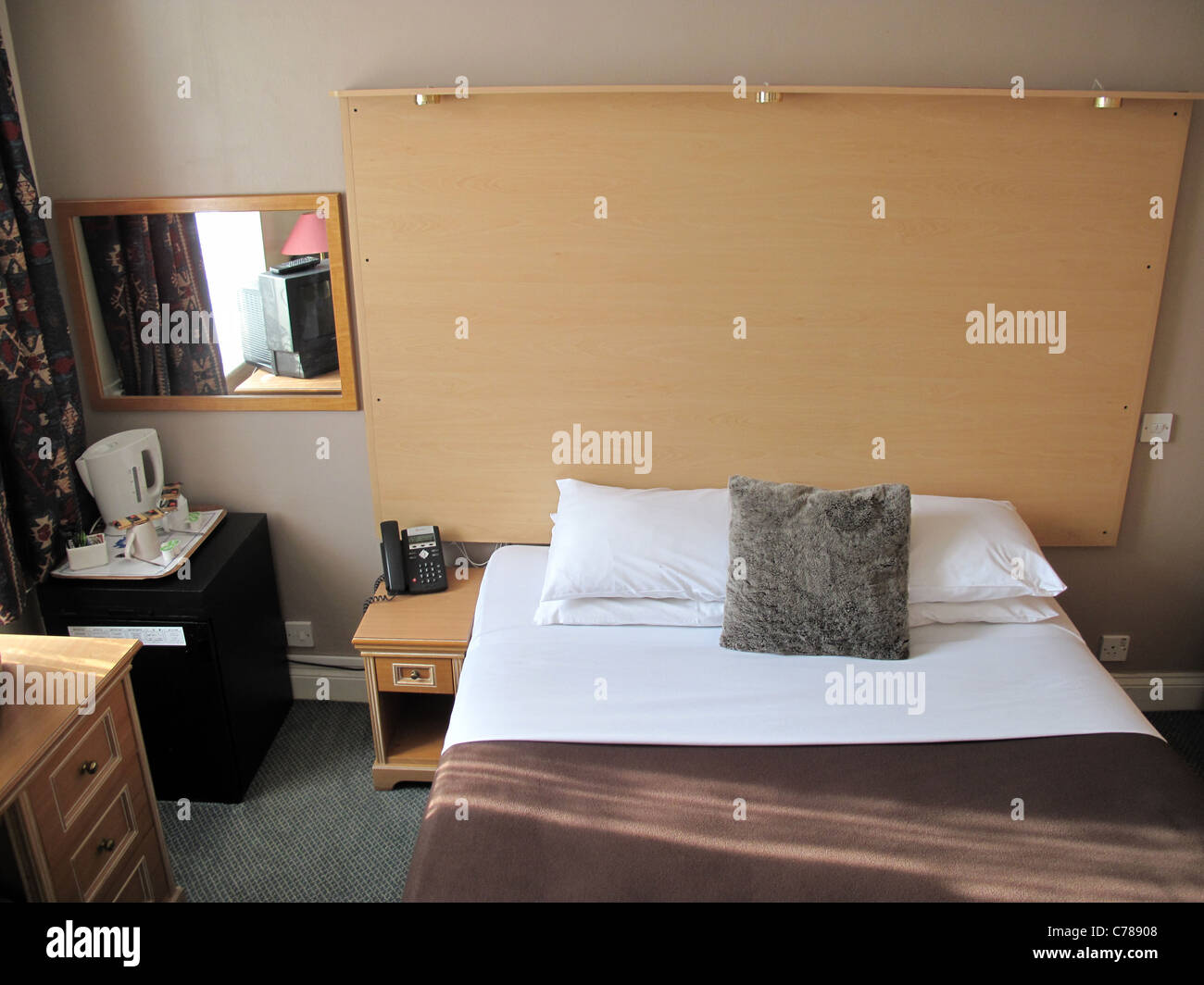 Cheap hotel room bed and mirror and table Stock Photo