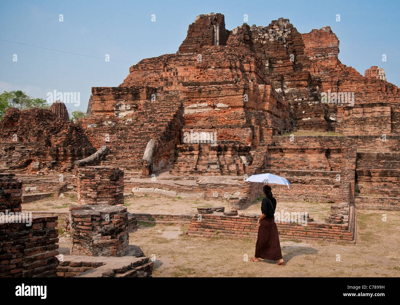 Woman visitor with umbrella at Wat Maha That Buddhist temple ruins, Ayutthaya, Thailand. Stock Photo