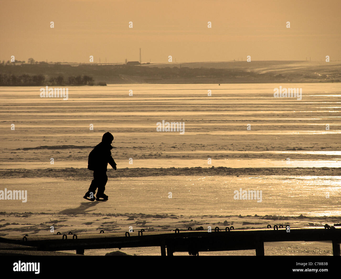 silhouette of a boy skating on a frozen river Stock Photo - Alamy