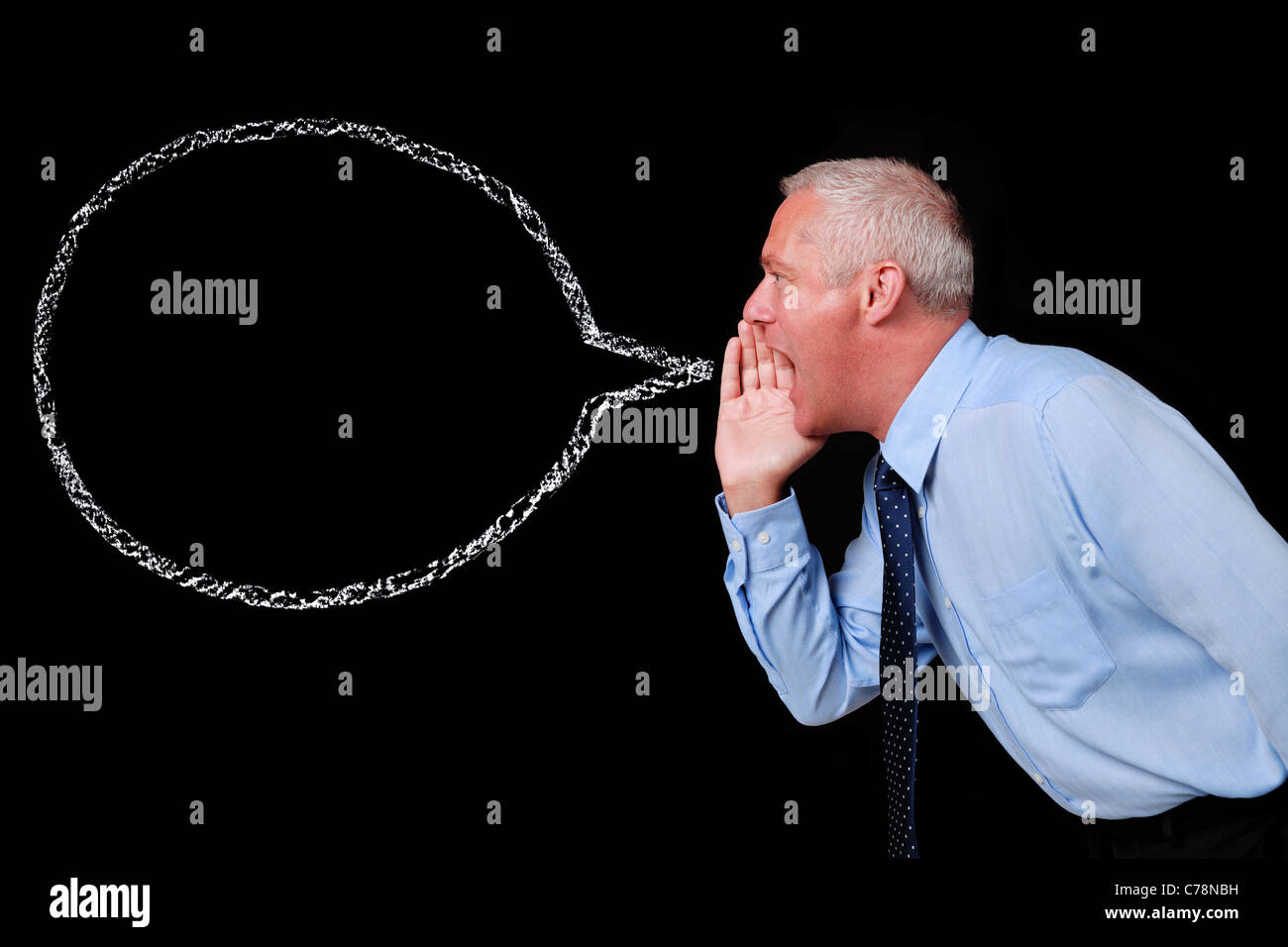 Photo of a mature businessman shouting against a black background, chalk speech bubble with copy space to add your own text. Stock Photo