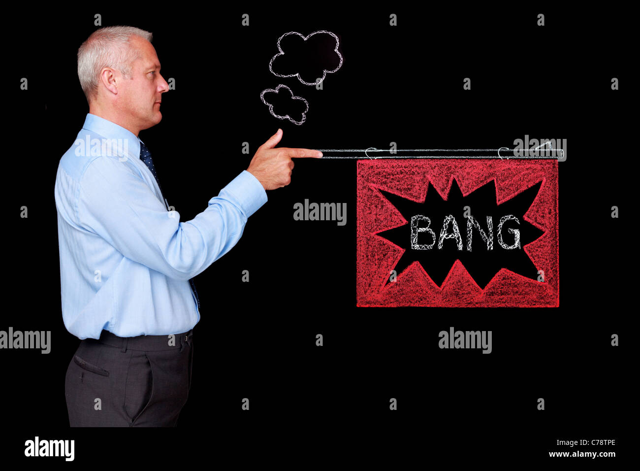 Photo of a mature businessman against a black background firing a chalk drawn gun with a BANG flag. Stock Photo