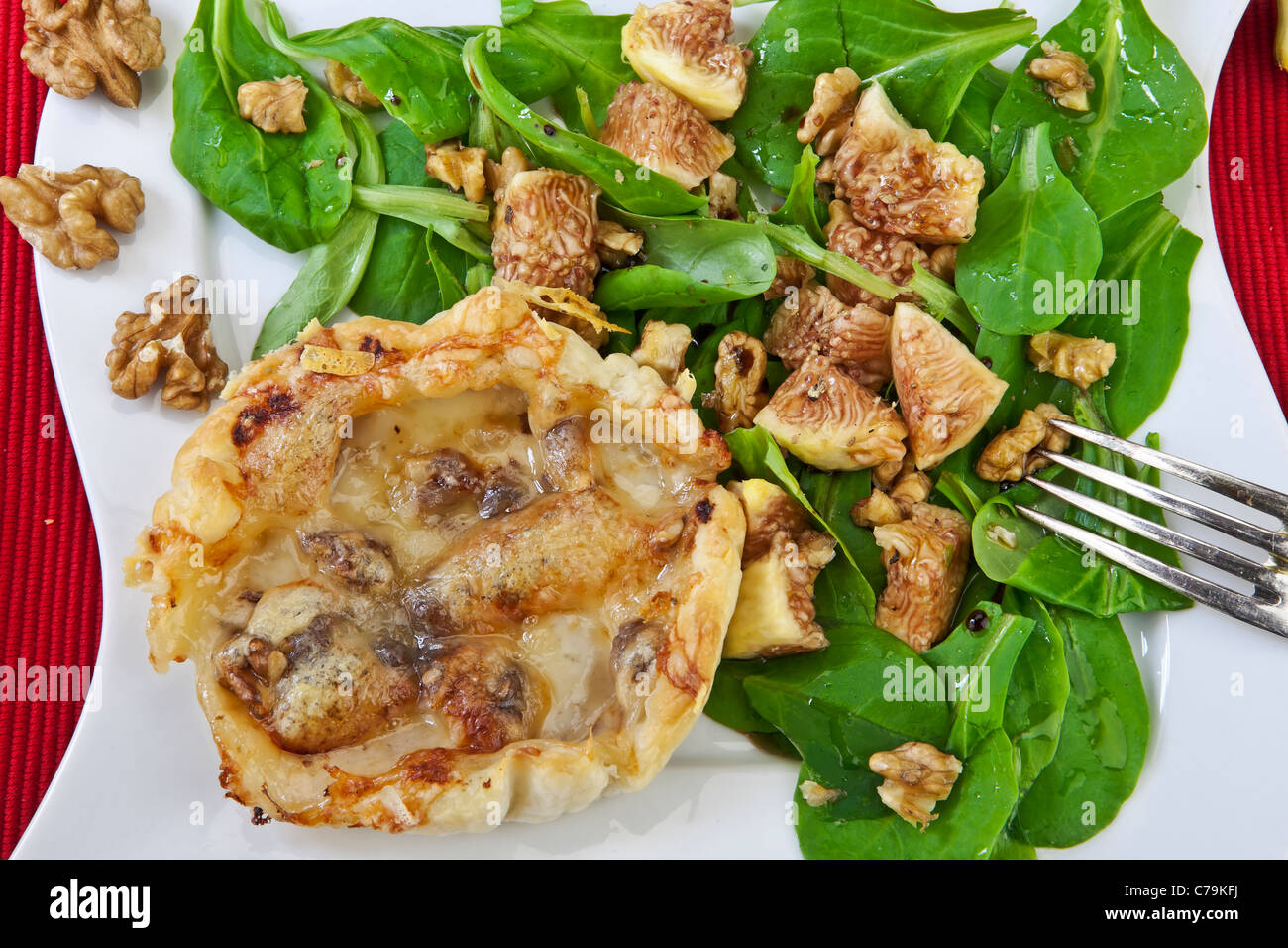 A puff pastry tart with pears and Vacherin cheese, served with a salad. Stock Photo
