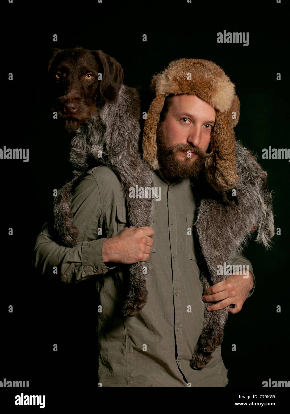 Studio portrait of young man carrying dog over shoulders Stock Photo
