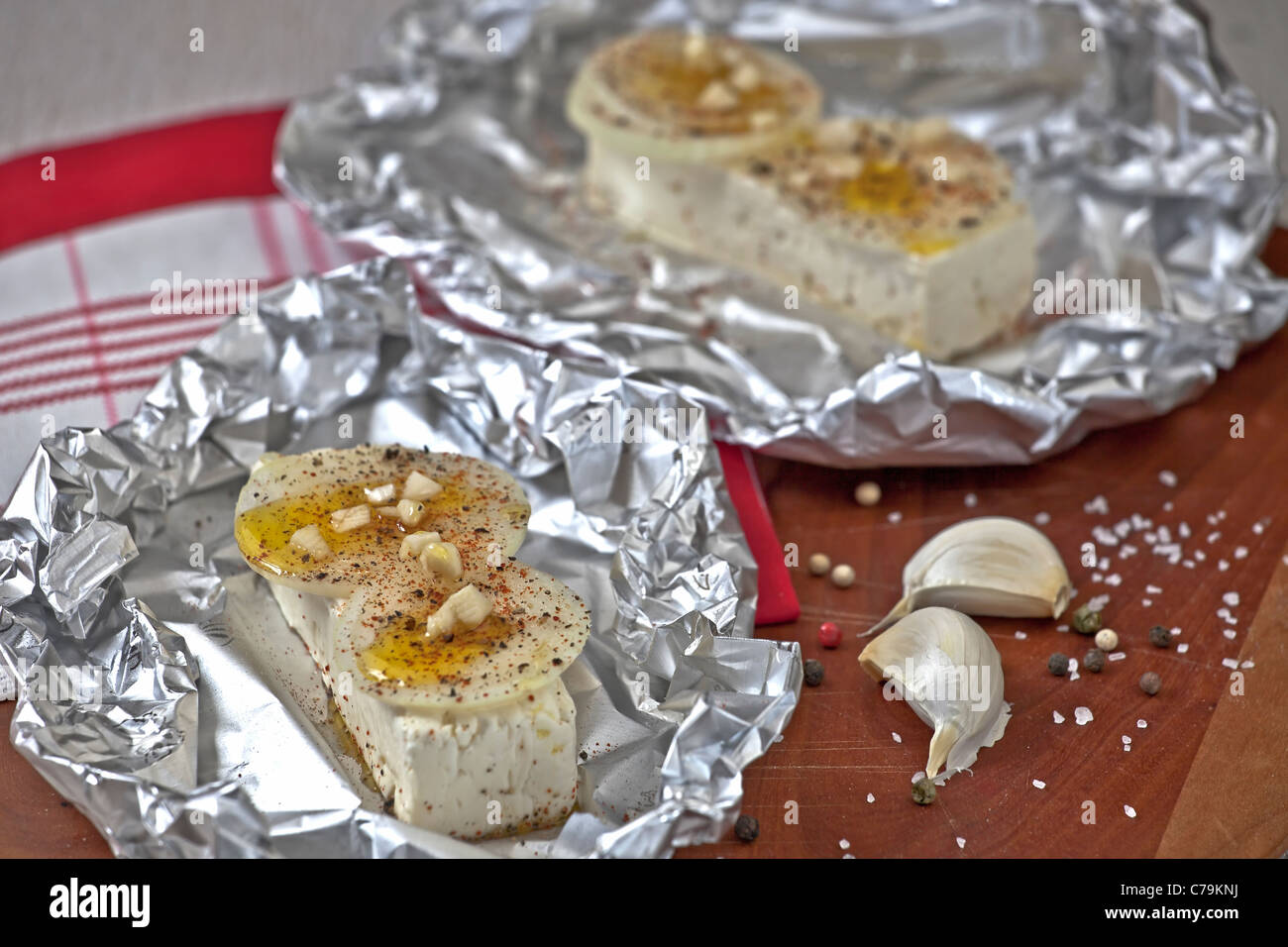 baked feta cheese with onions and garlic in aluminum foil Stock Photo