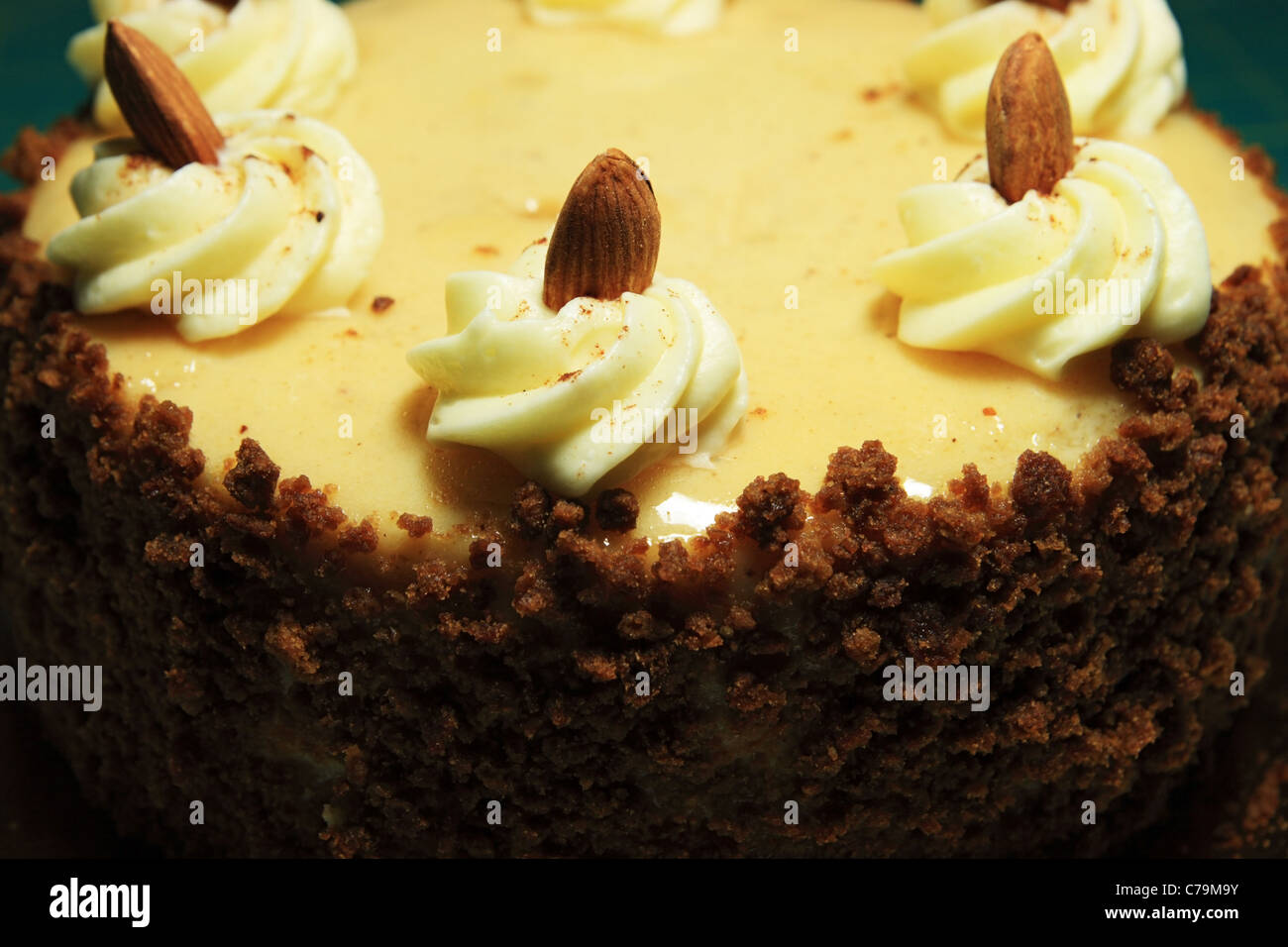 close up of yellow frosted cake with almonds and crumble sides Stock Photo