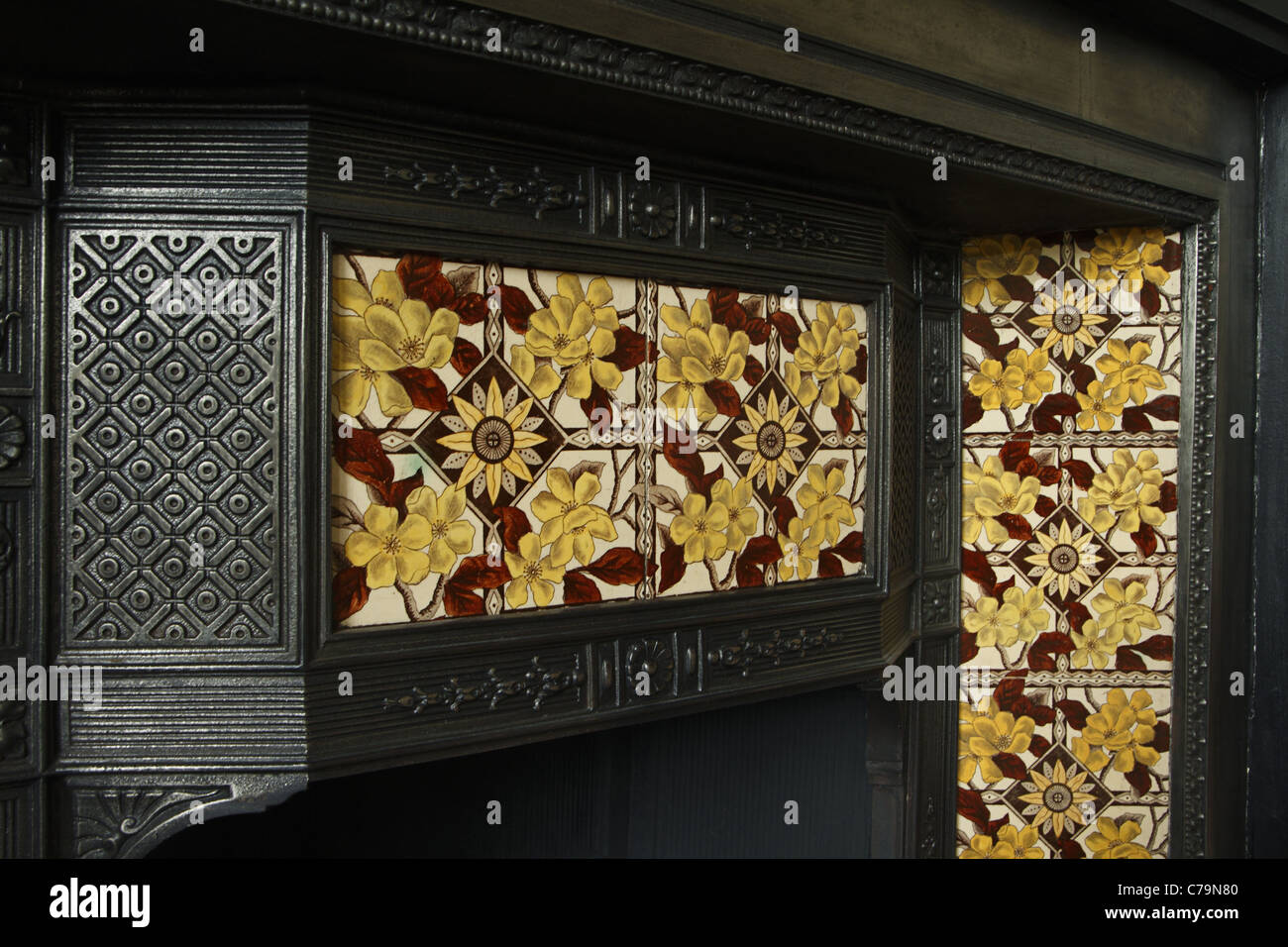 Victorian cast-iron fireplace with inlaid ceramic tiles. Stock Photo