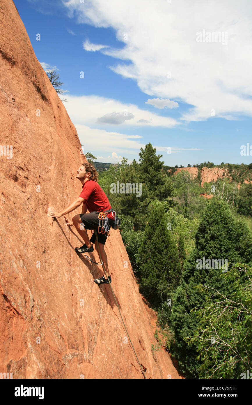 a man in red leading on a sandstone slab rock climb Stock Photo