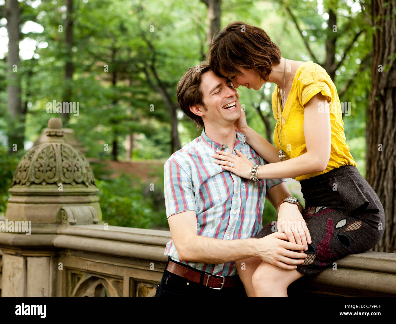 USA, New York State, New York City, Young couple in park, woman sitting on railing Stock Photo