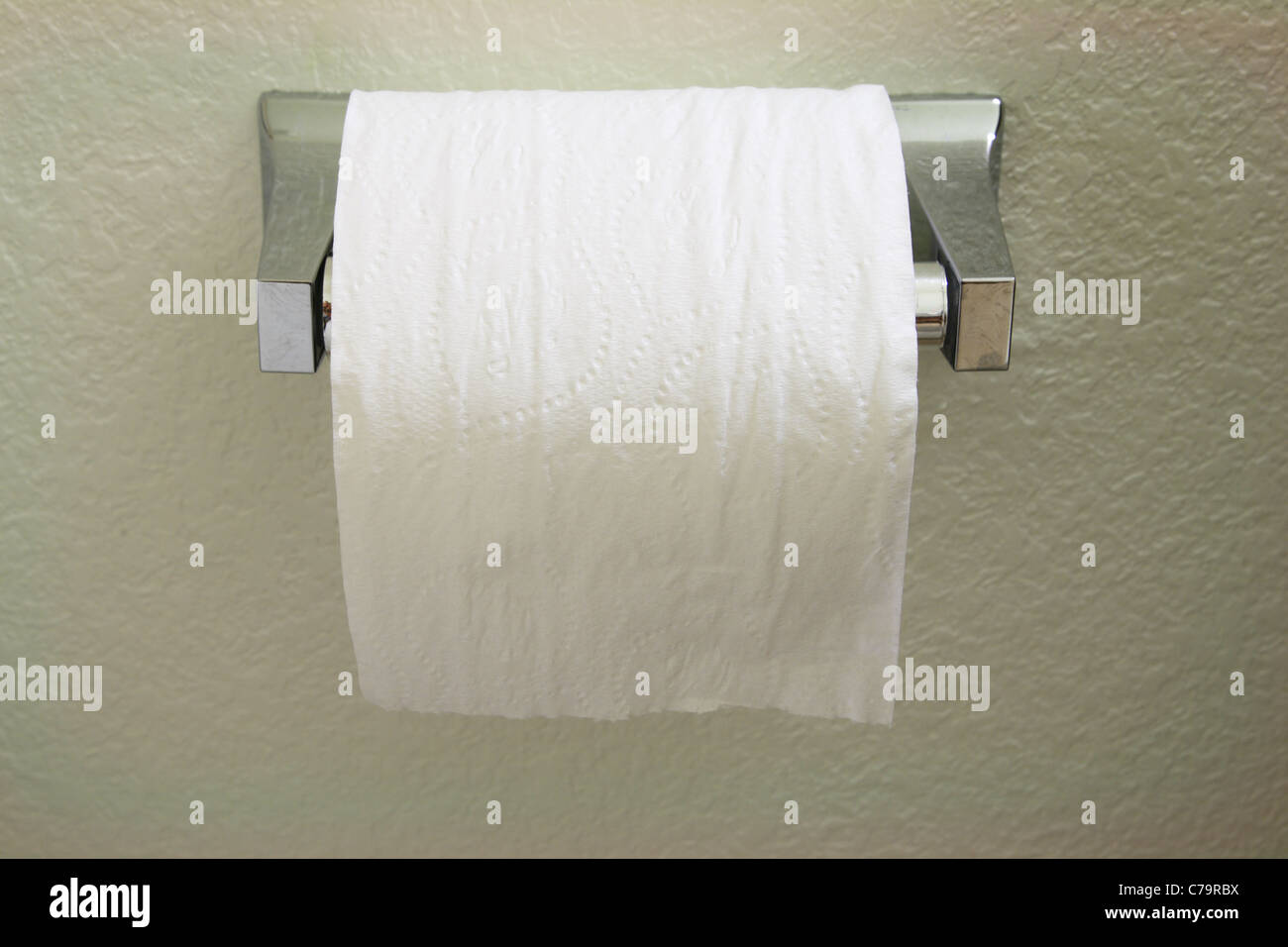 a toilet paper roll dispenser with the paper feeding over the top towards the front Stock Photo