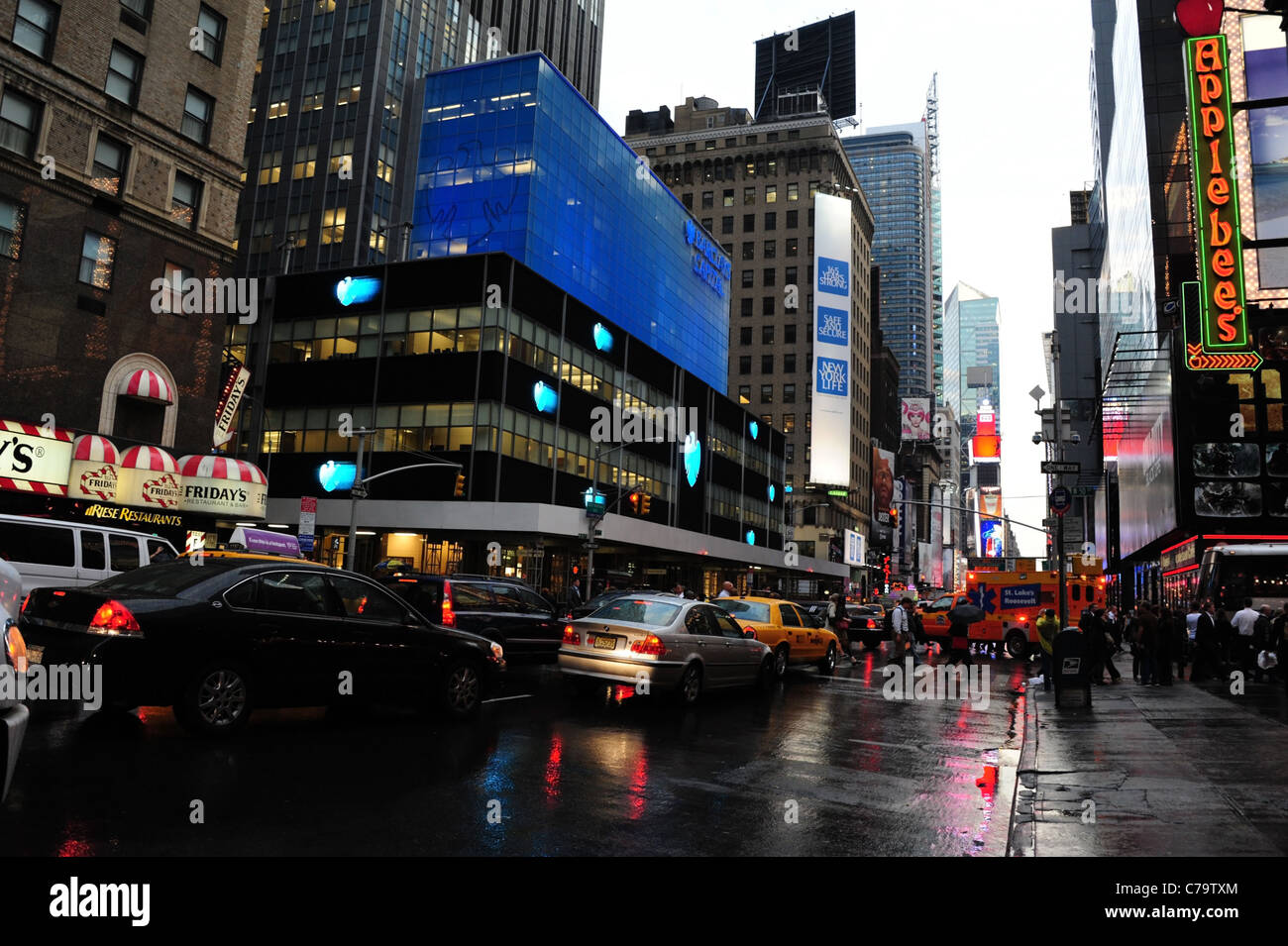Traffic people blue neon Barclay's Bank, red Applebee's sign, wet rain tarmac 7th Avenue