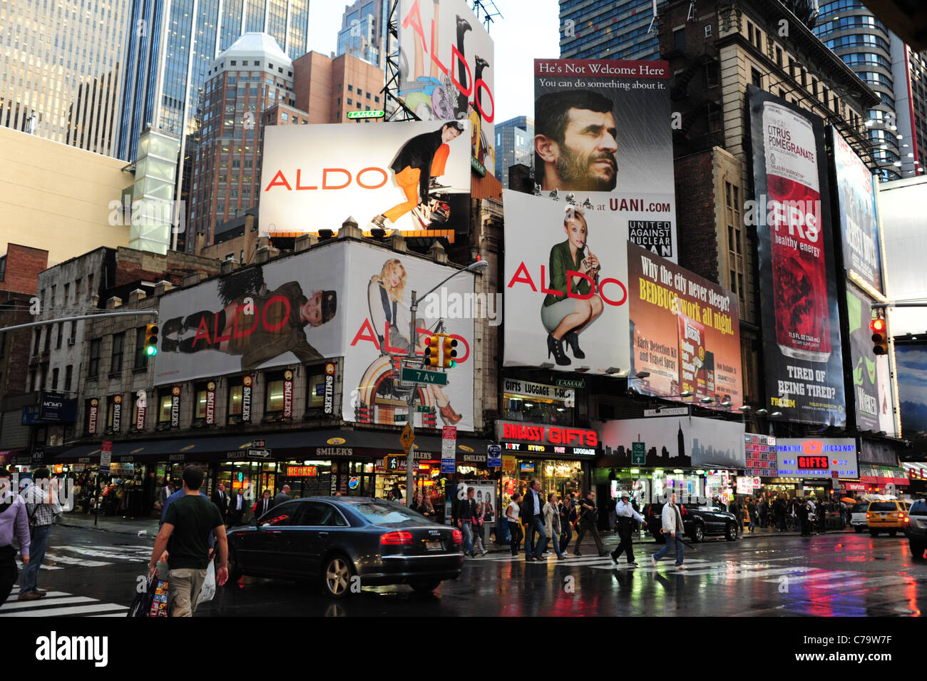 Car and people crossing wet tarmac blue red neon 7th Avenue, front skyscraper adverts, 48th Street intersection, New York City Stock Photo