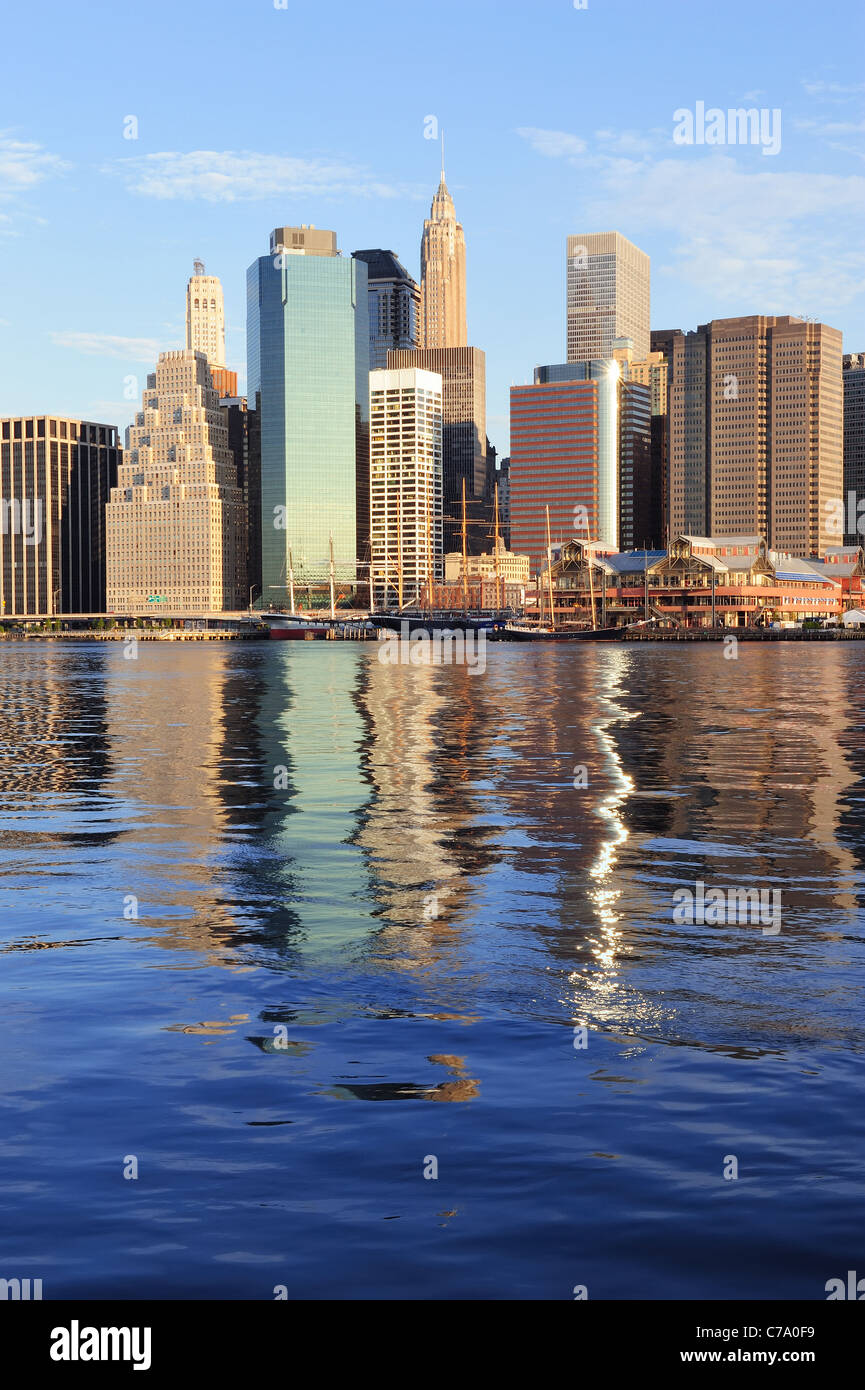 Lower Manhattan skyline panorama over East River with reflection and ...