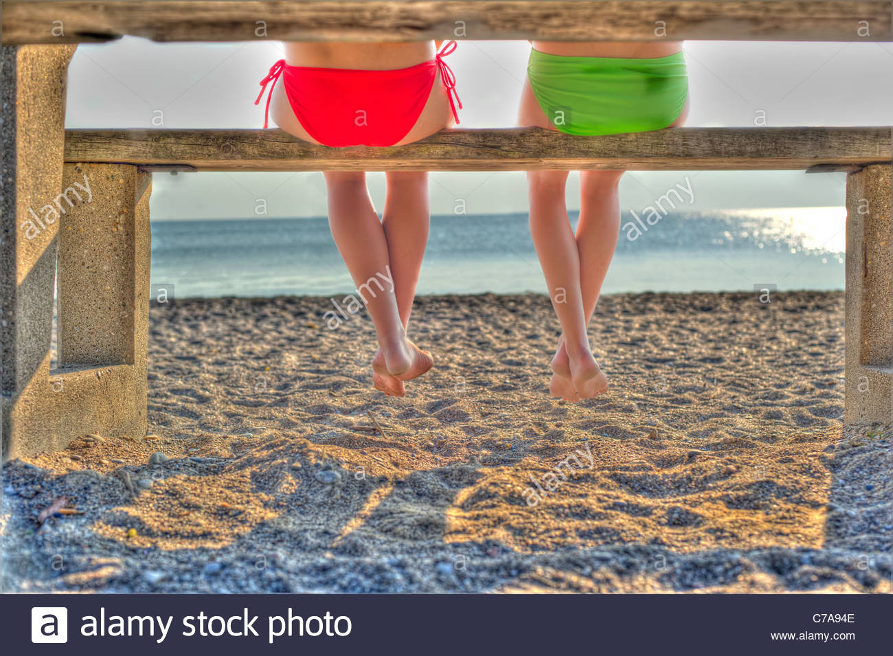 legs feet and butts of two girls at a picnic table at a beach Stock Photo -  Alamy