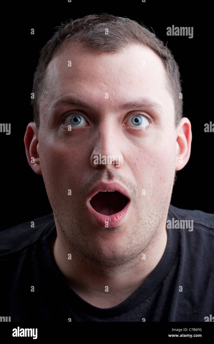 A shocked or surprised middle aged man over a dark background. Stock Photo