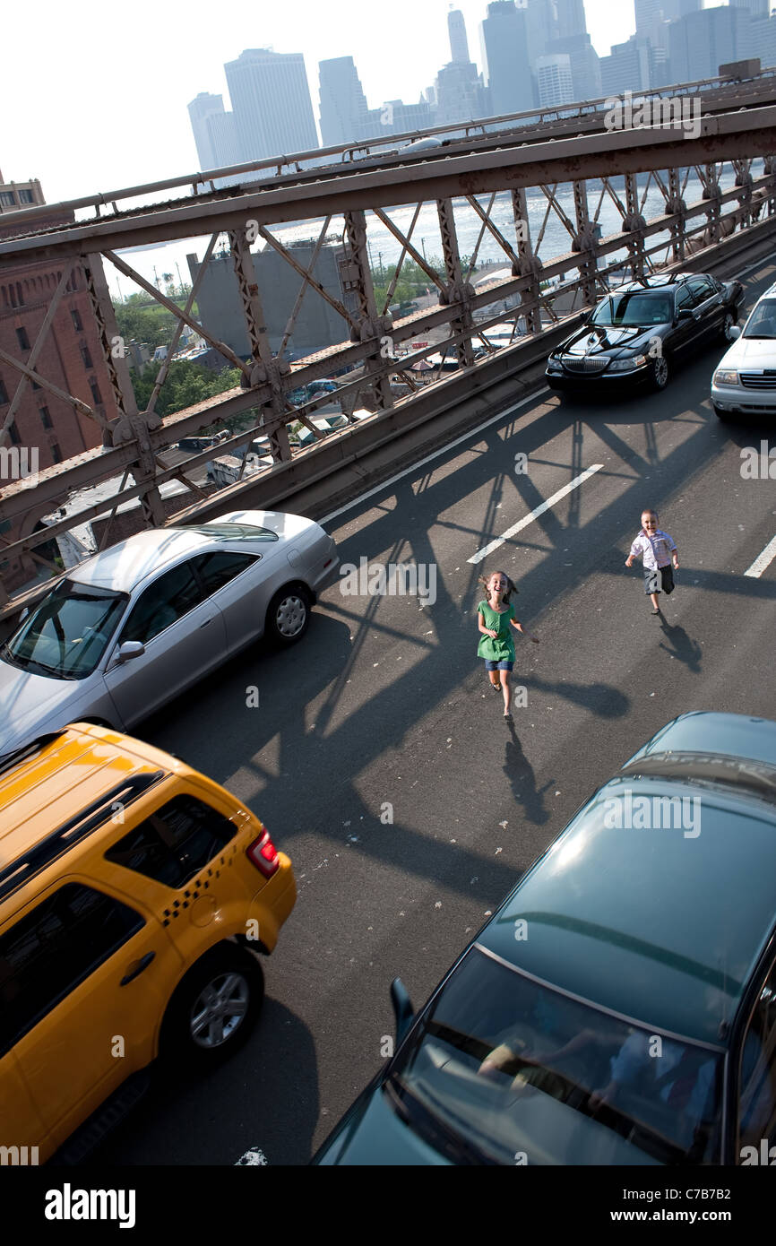 Two young children running wild on the Brooklyn Bridge in between traffic. Stock Photo