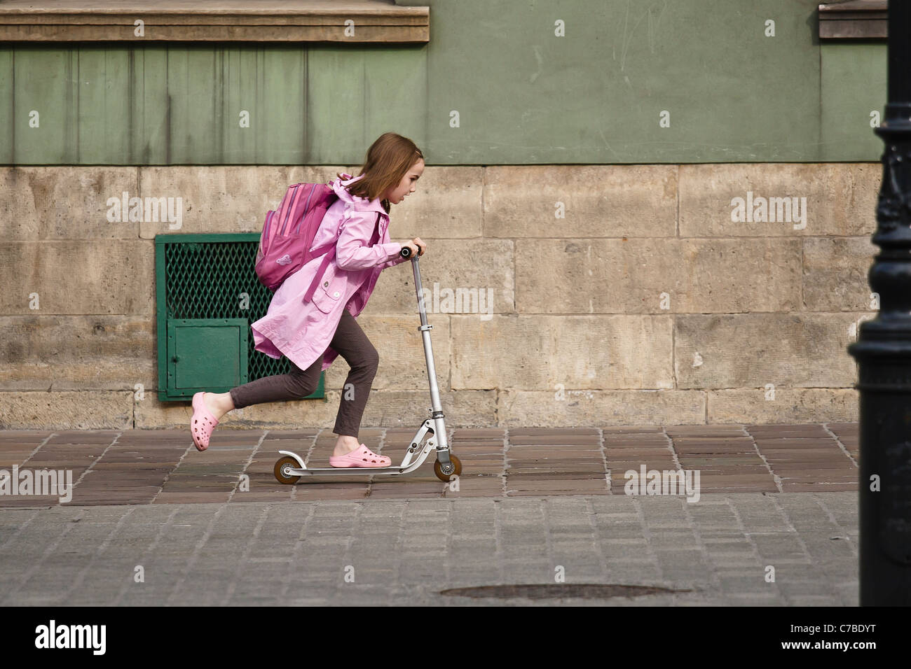 Girl  with schoolbag on a scooter. Stock Photo