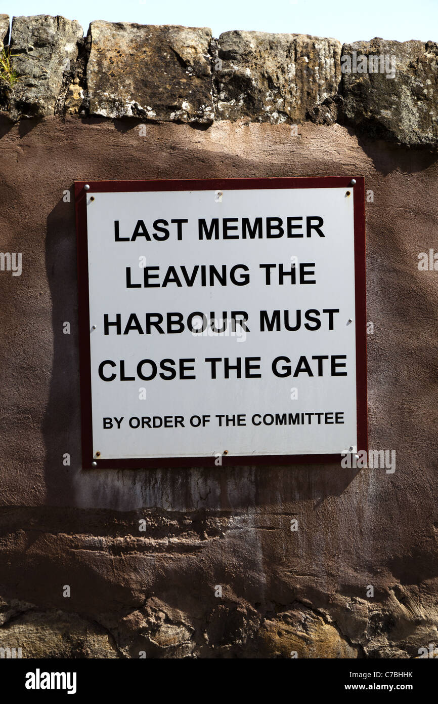 Notice by order of a committee displayed in a harbour stating ' last member leaving the harbour must close the gate' Stock Photo