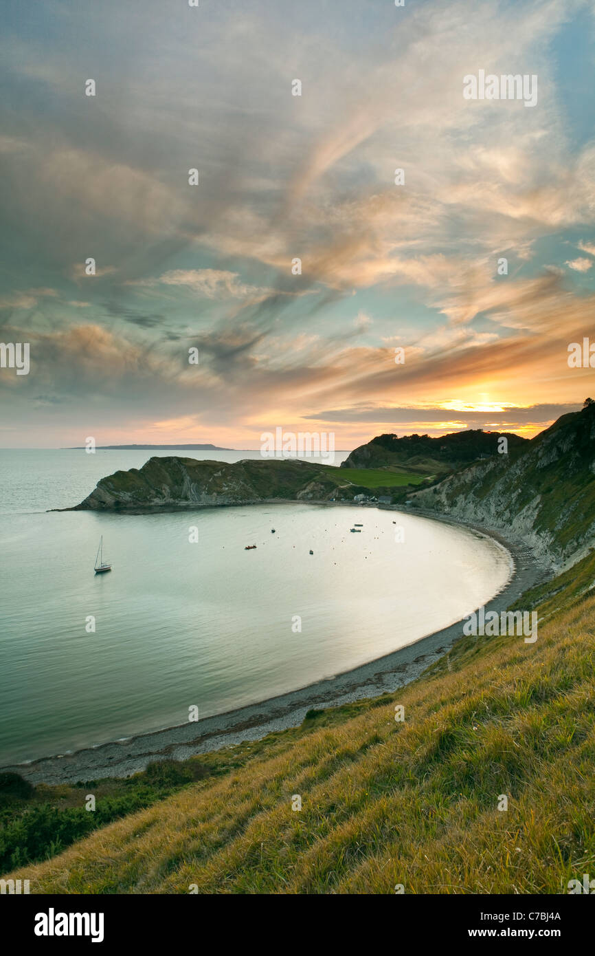A view of Lulworth Cove, part of the Jurassic Coast in Dorset at sunset with Portland Bill in the distance Stock Photo