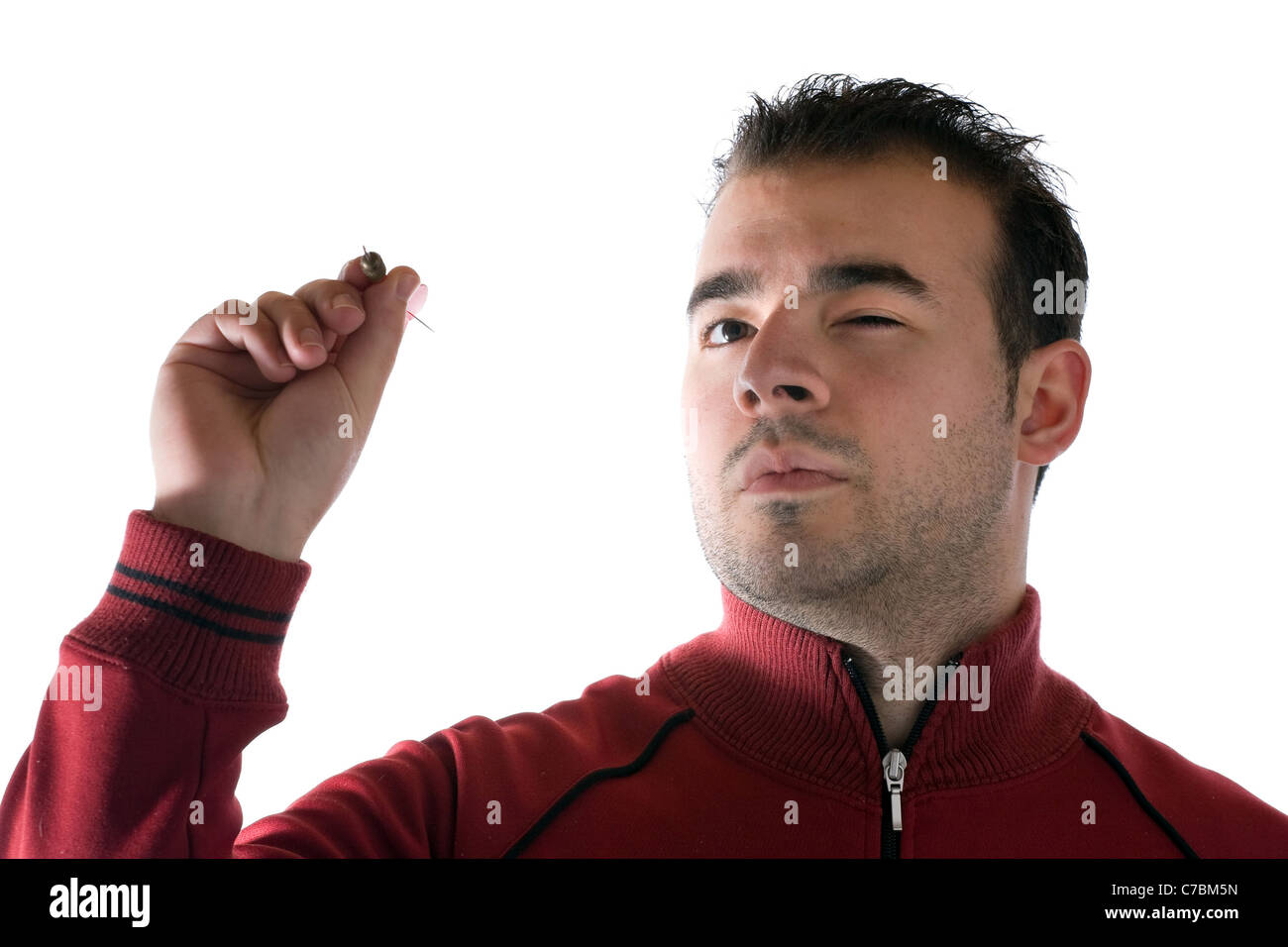 A young man aims a dart as he gets ready to throw it at the target. Stock Photo