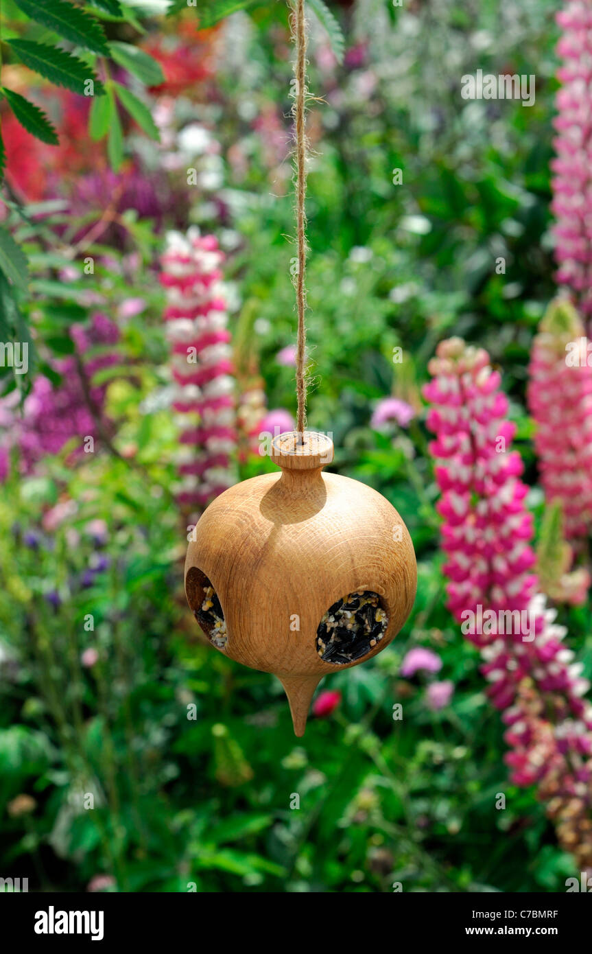 Wooden Wood Fancy Bird Feeder In Garden With Pink And White Lupins