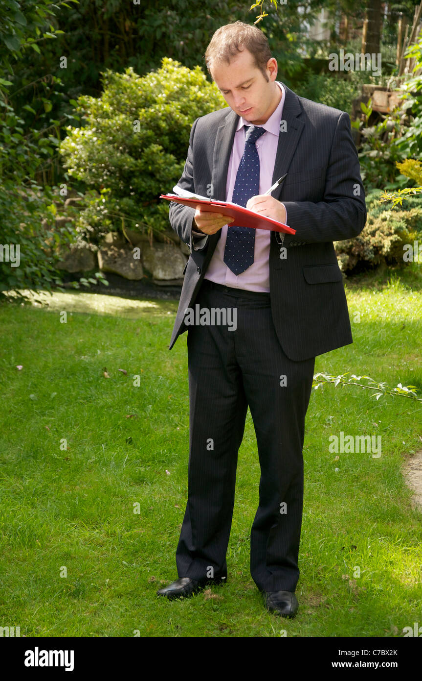 Surveyor inspecting exterior of property and taking notes/preparing a sketch. Stock Photo