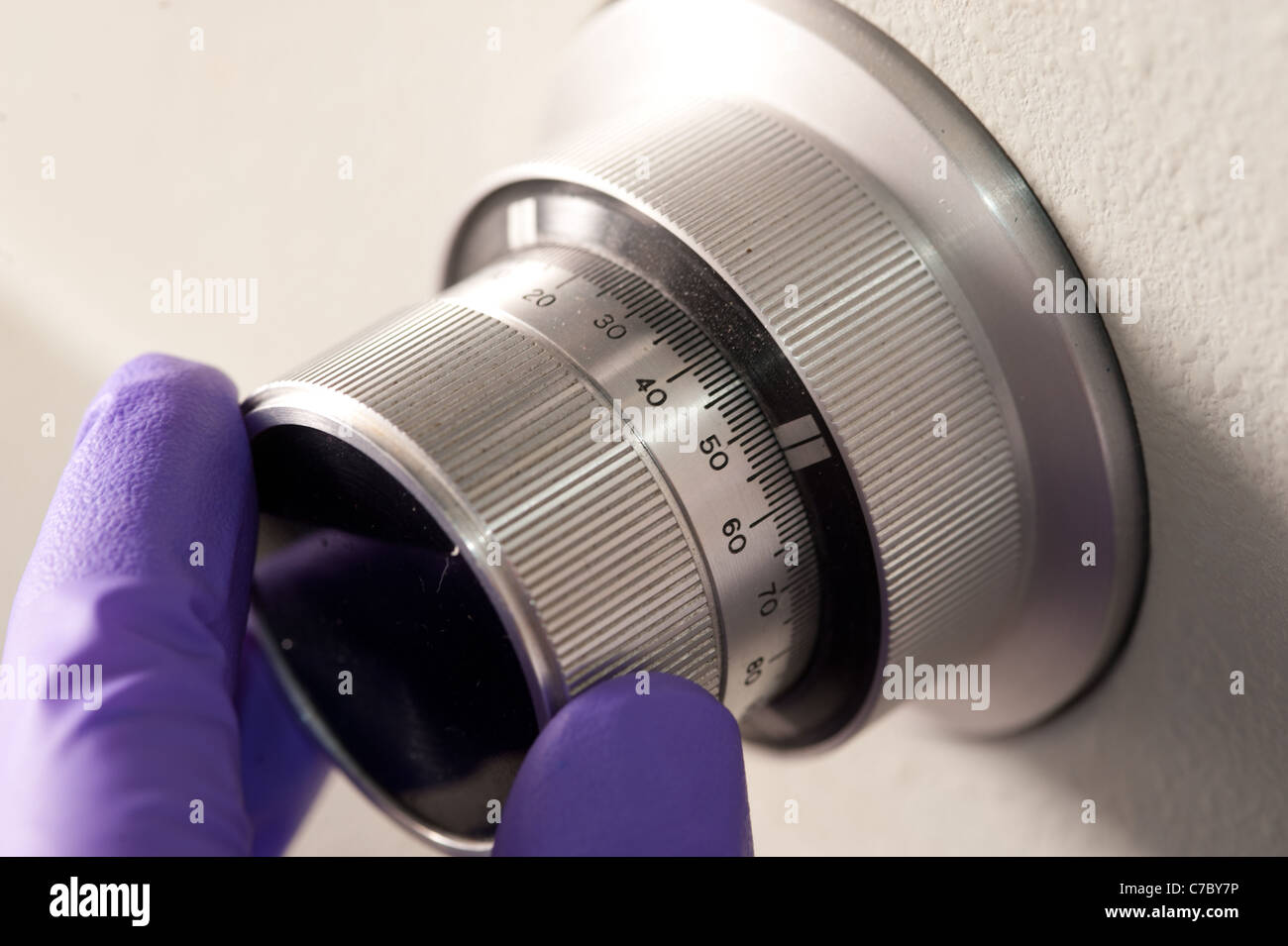 Gloved fingers turning a metal dial knob Stock Photo Alamy