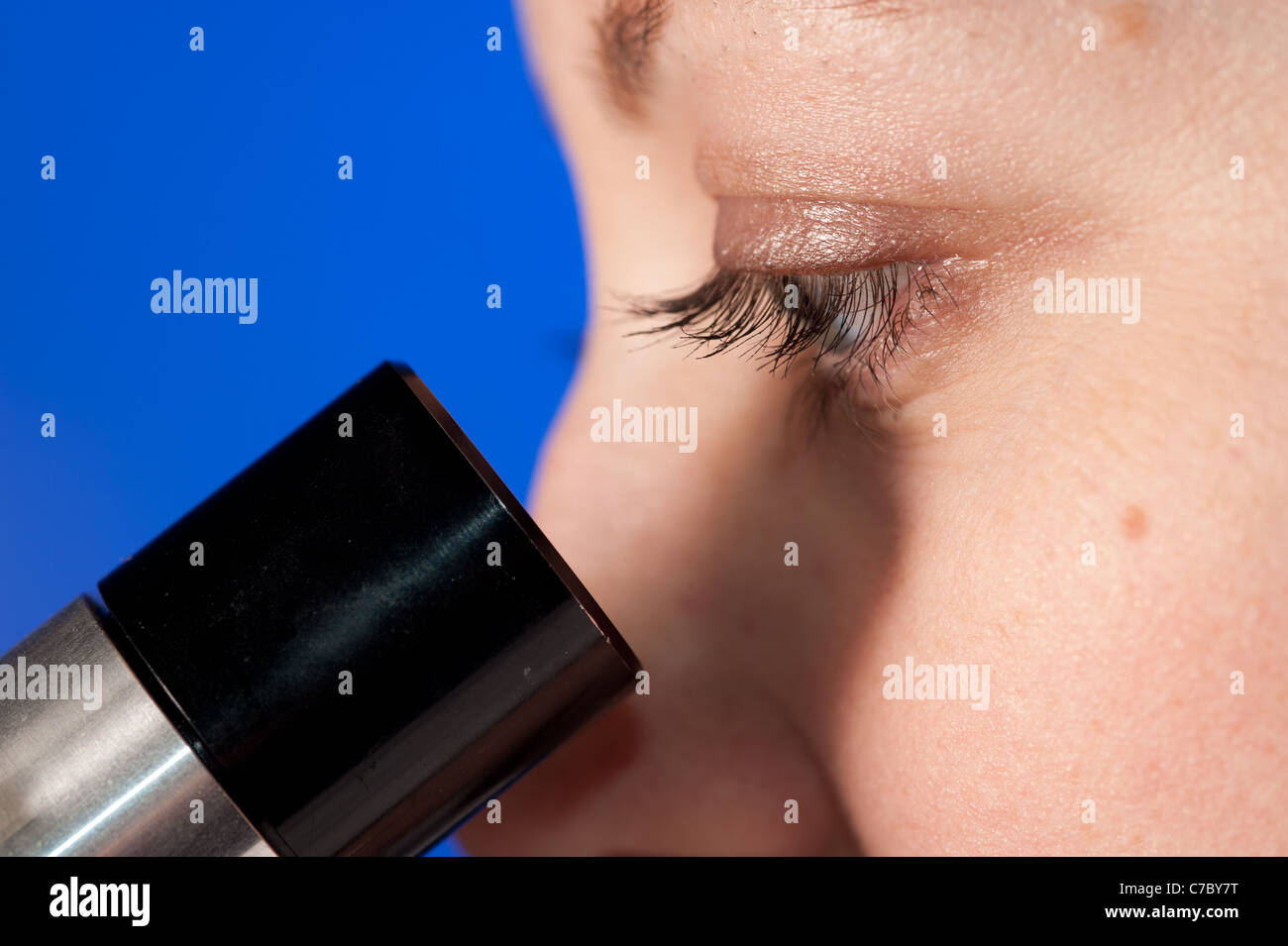Woman's eyes looking into a microscope Stock Photo
