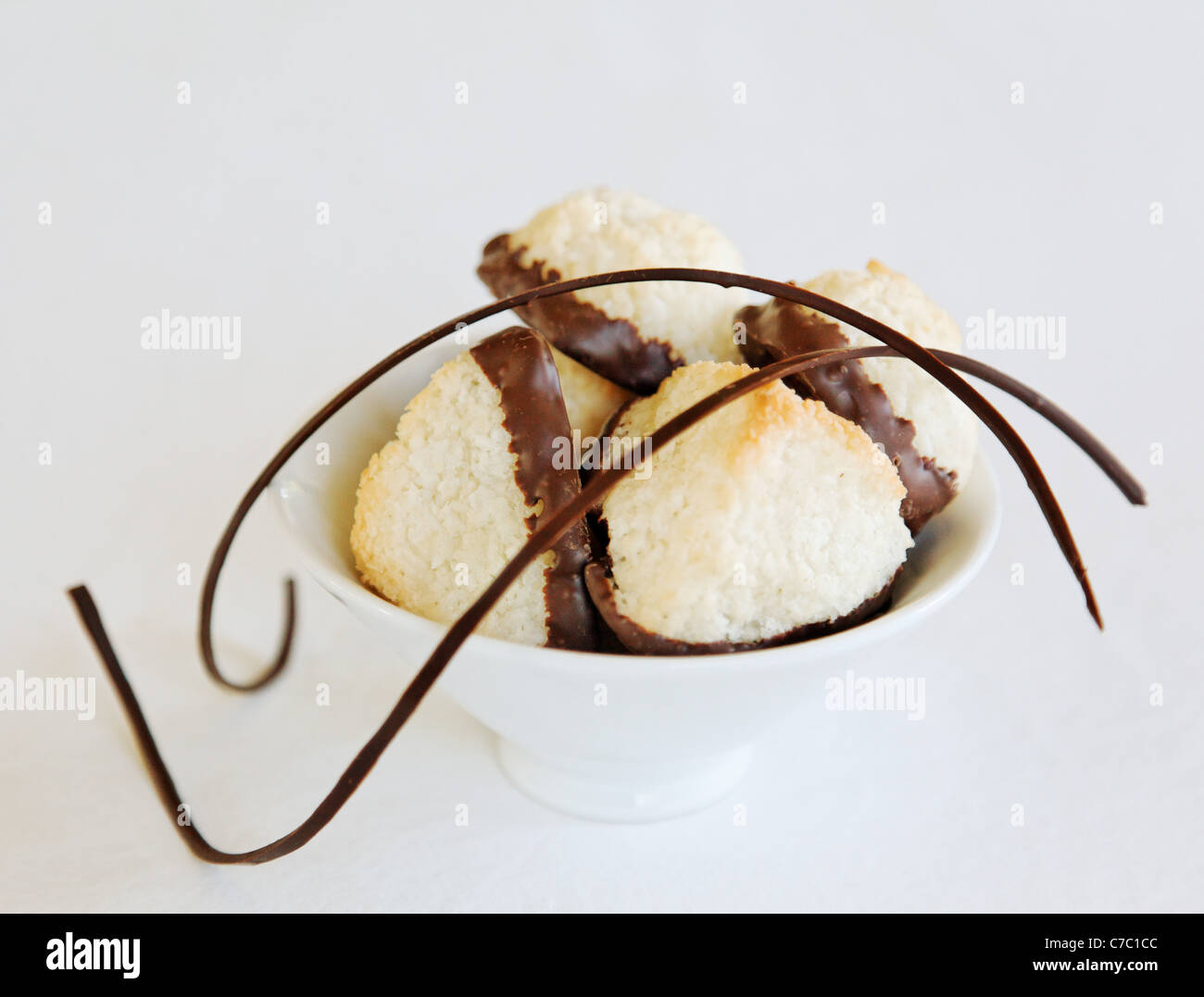 Coconut macaroons dipped in chocolate in white bowl garnished with chocolate swirl, by pastry chef Laurie Pfalzer, Pastry Craft Stock Photo