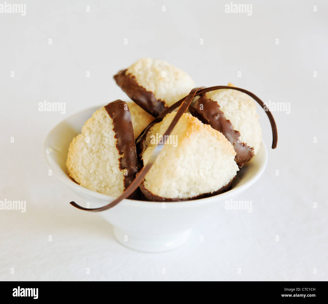 Coconut macaroons dipped in chocolate in white bowl garnished with chocolate swirl, by pastry chef Laurie Pfalzer, Pastry Craft Stock Photo