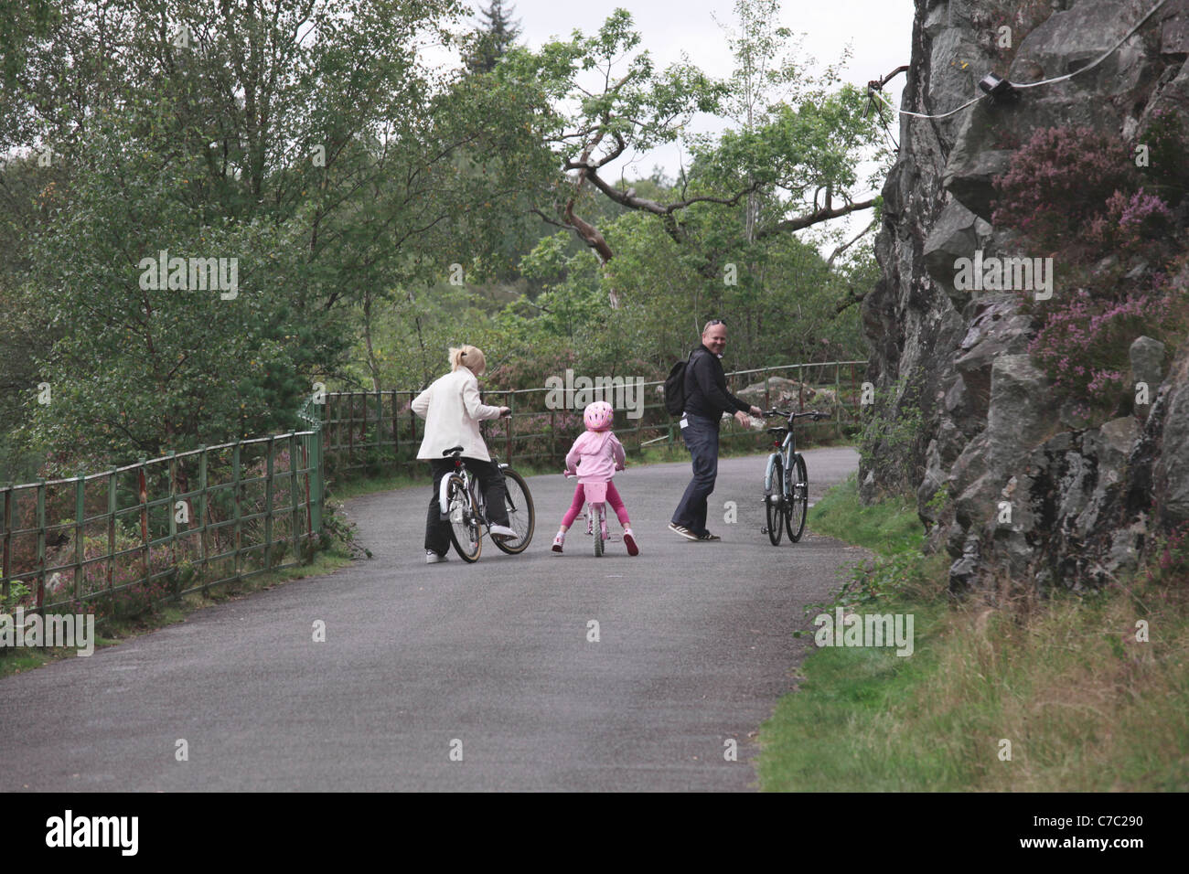 Small girl on bicycle with parents beside Loch Katrine in the Trossachs Scotland Stock Photo