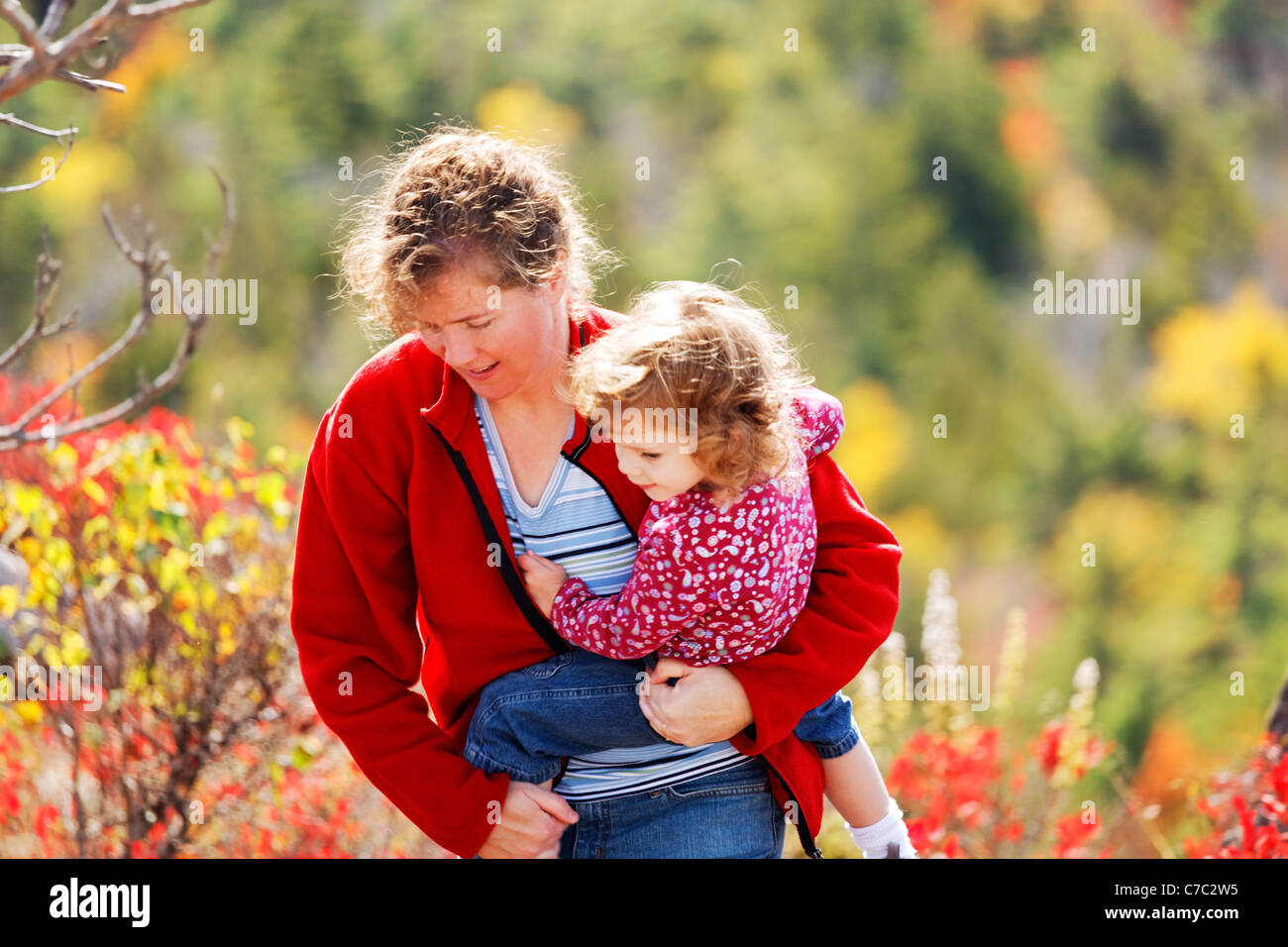 Woman carrying little girl in fall colored landscape, Mount Desert