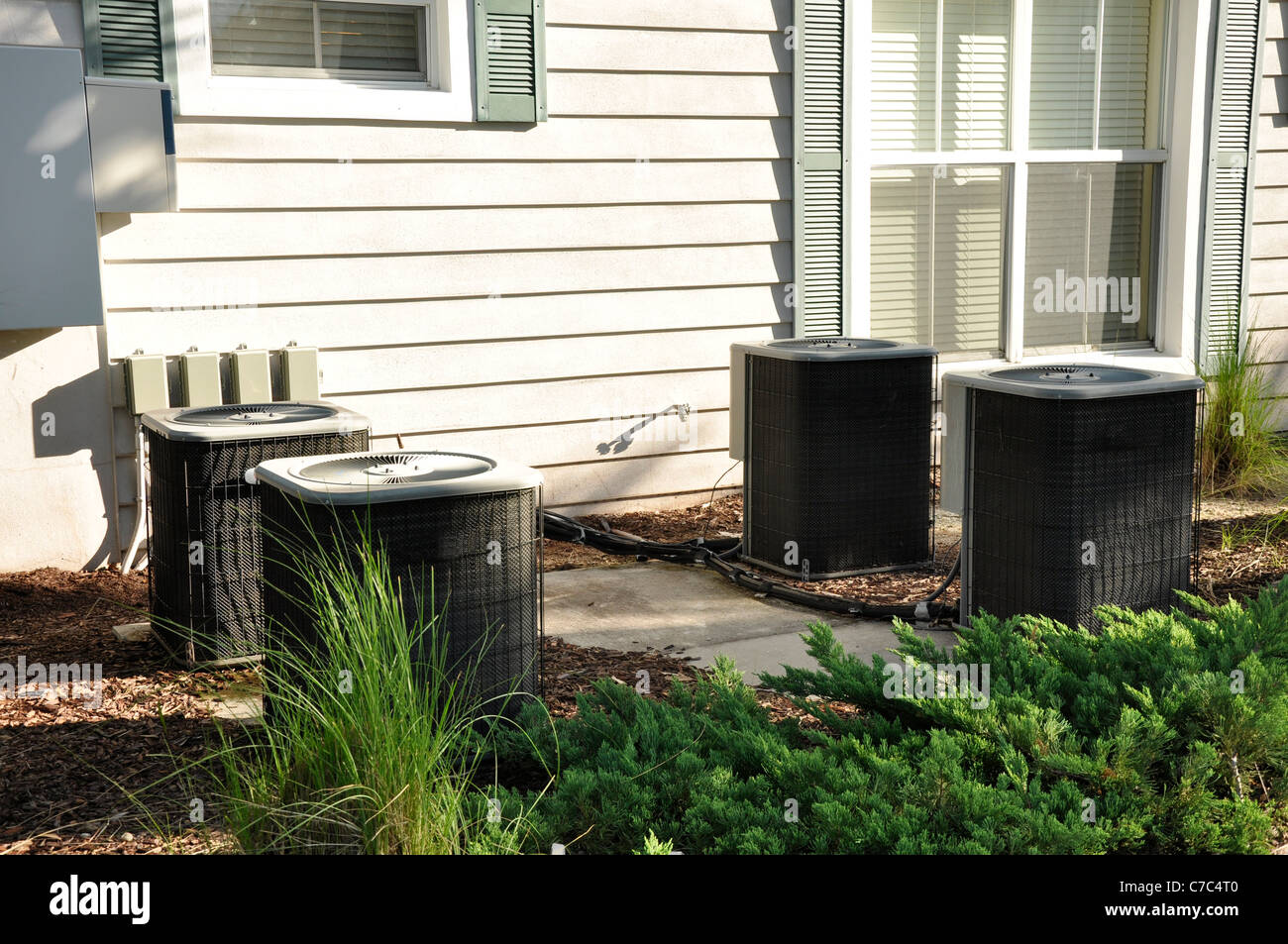 Several outdoor central air conditioning units by a building Stock