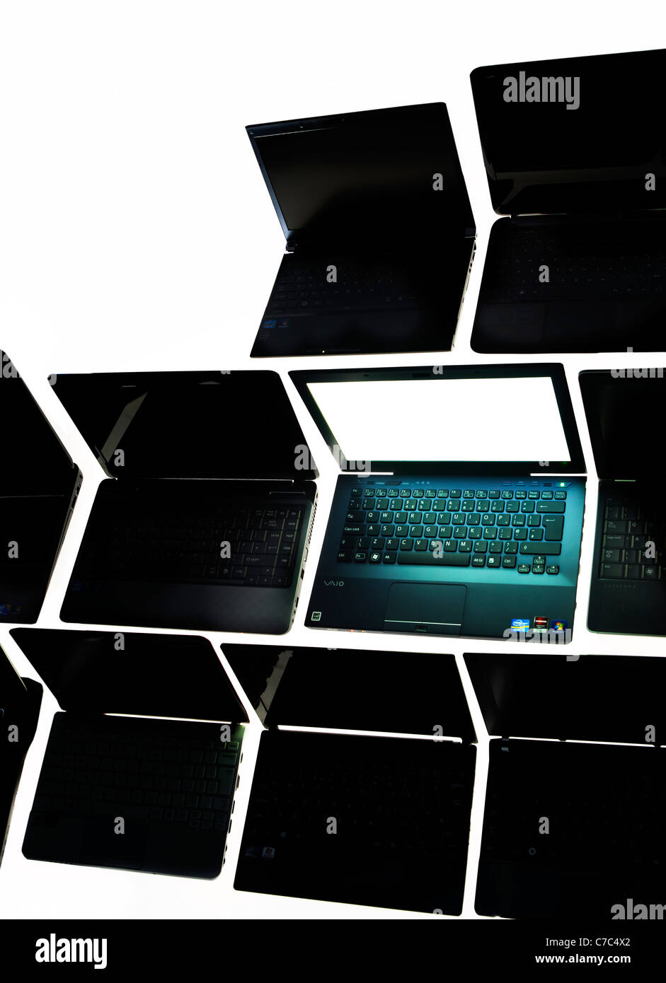 Lots of laptops, only one is powered on, the rest are in dark ess Stock Photo