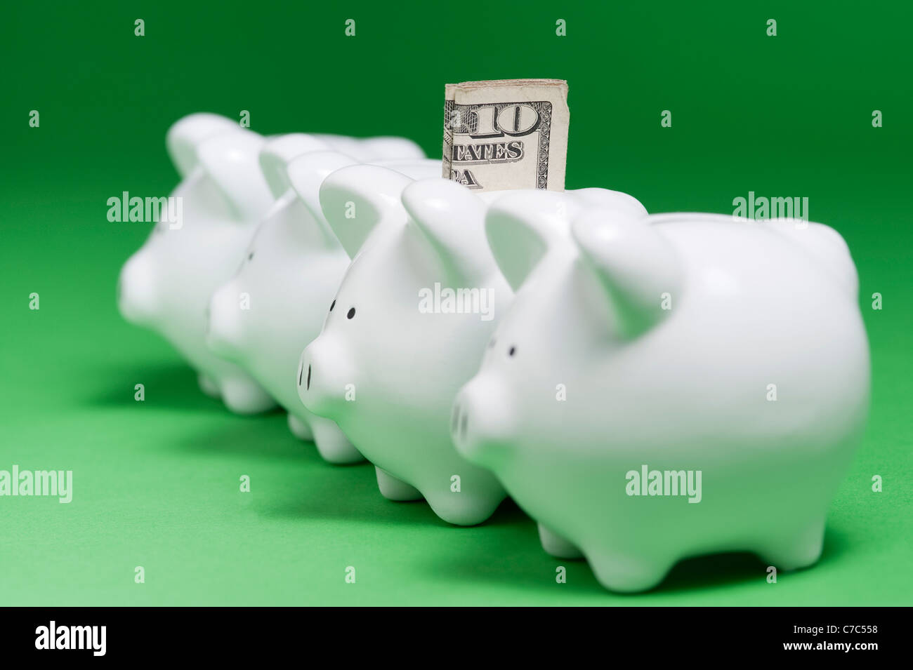 Piggy banks lined up in a row with one piggy bank having a ten dollar