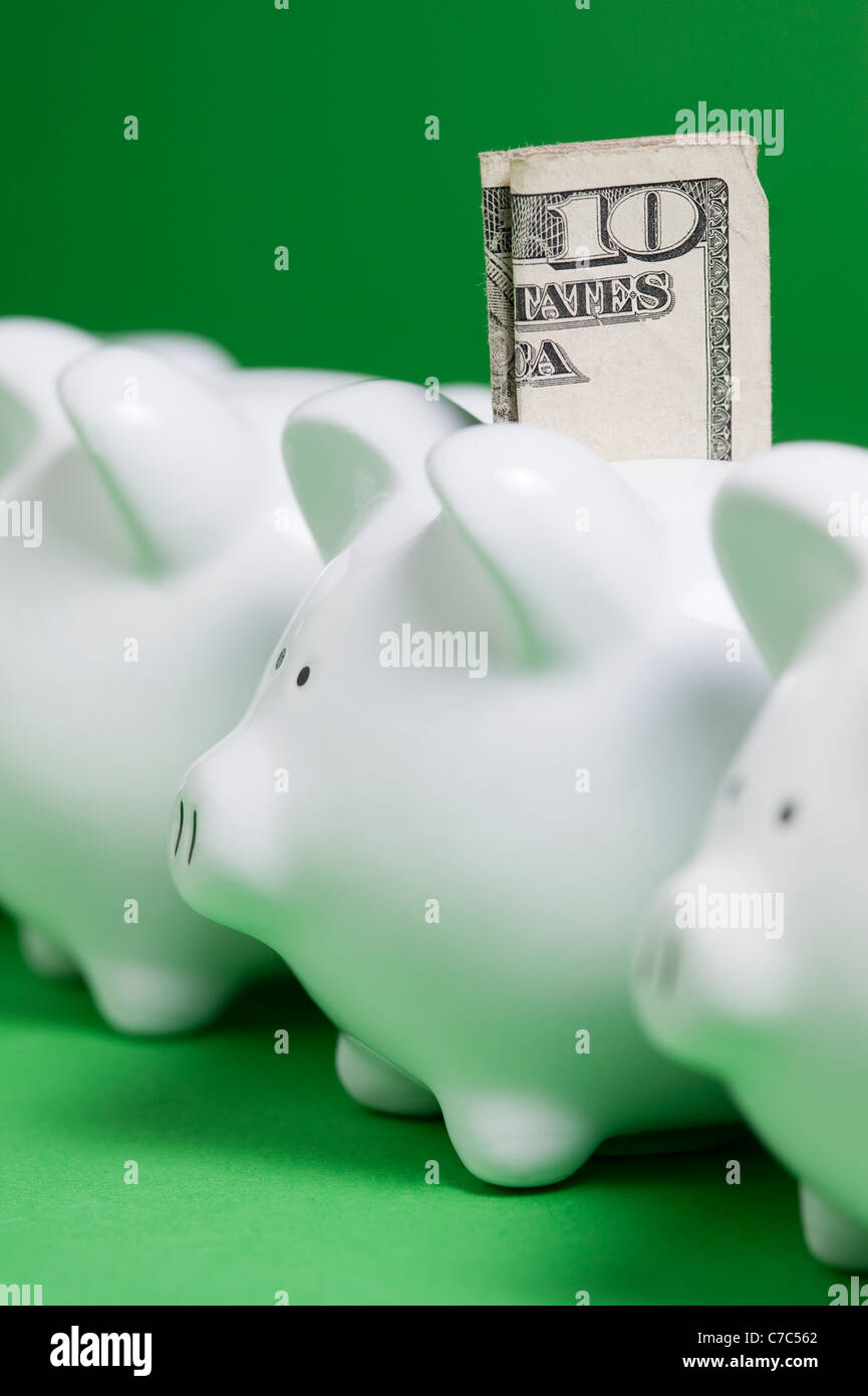 Rows of Piggy banks with money coming out of coin slots Stock Photo - Alamy