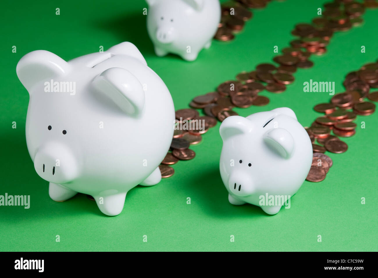 Group of Piggy Banks leaking pennies out back end losing money and