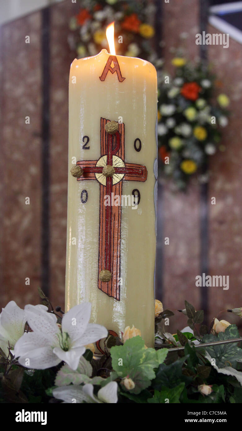 Easter candle, lit and decorated with flowers. Stock Photo