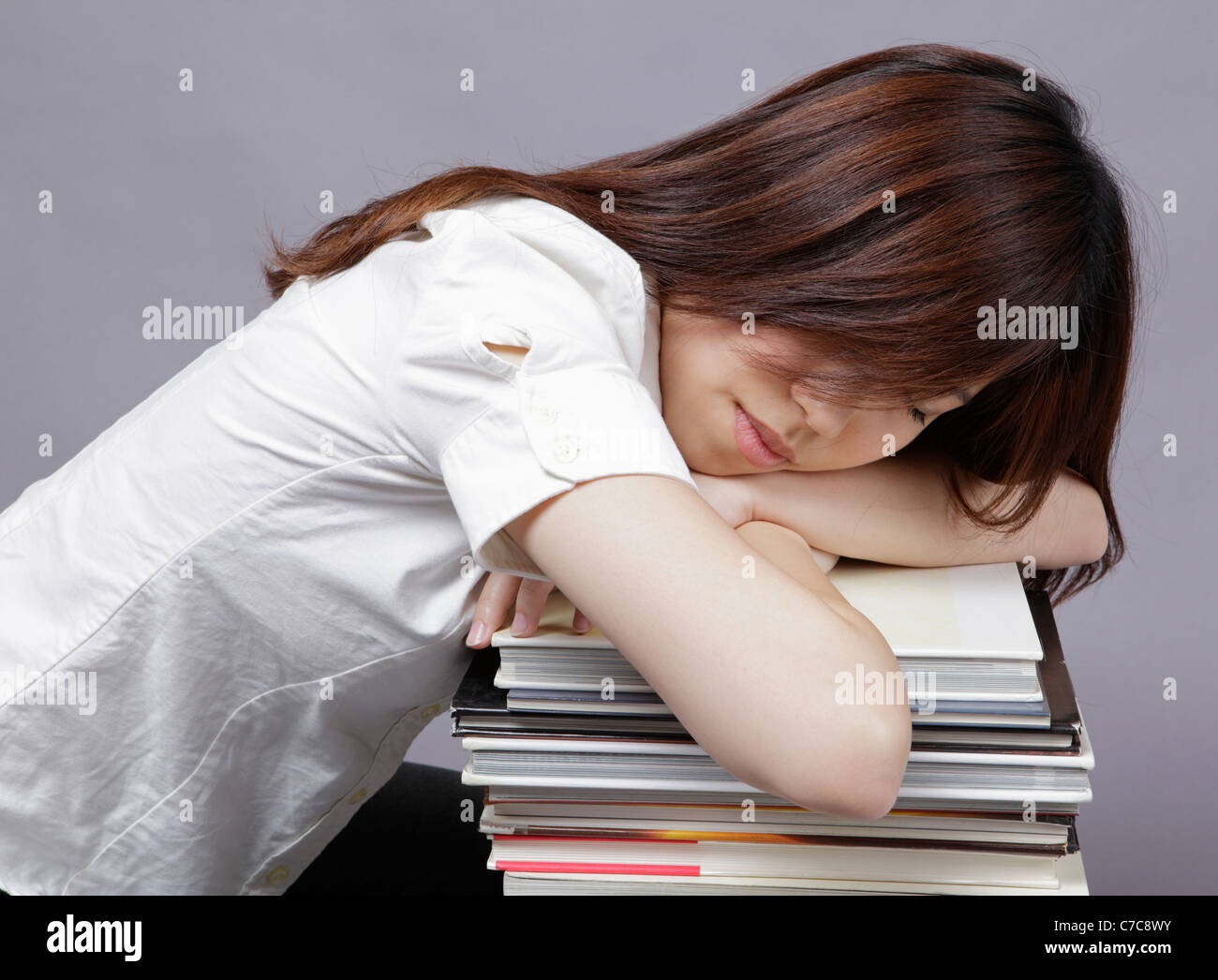 Girl rests on a pile of books Stock Photo - Alamy