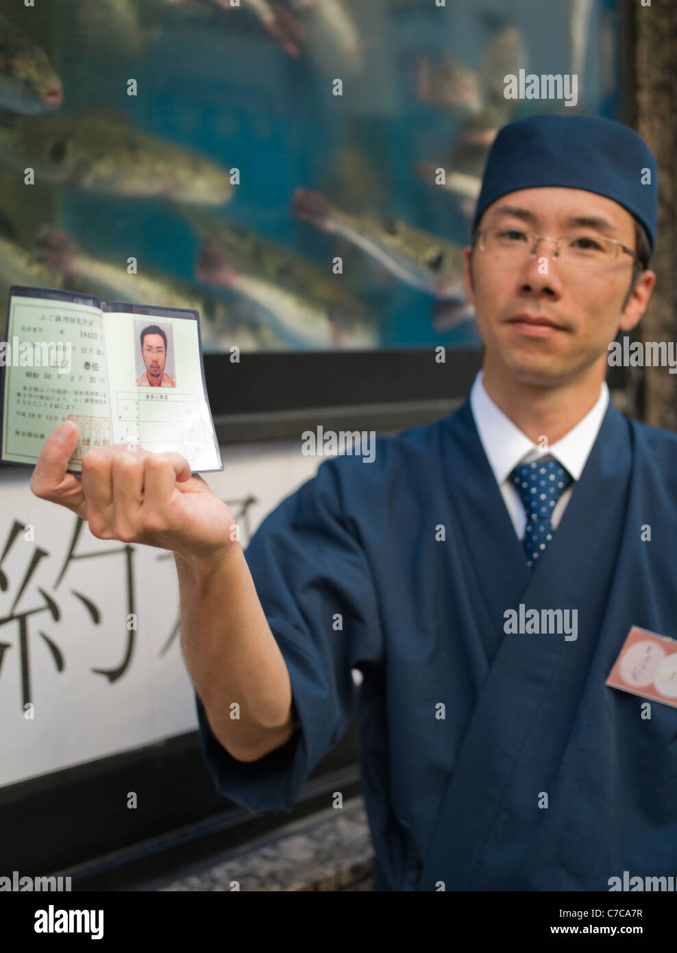 A Japanese Fugu chef shows his Fugu license outside the Shinjuku, Tokyo fugu restaurant at which he works Stock Photo