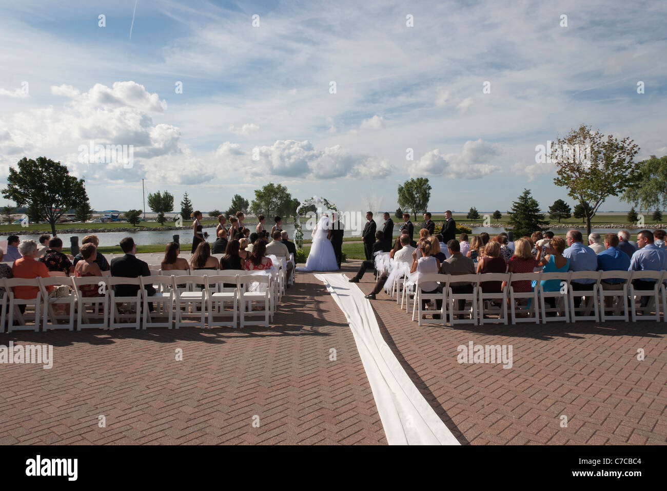 Outside wedding ceremony during beautiful summer day.Bride,groom, priest, bridesmaids, groomsmen and whole wedding party. Stock Photo