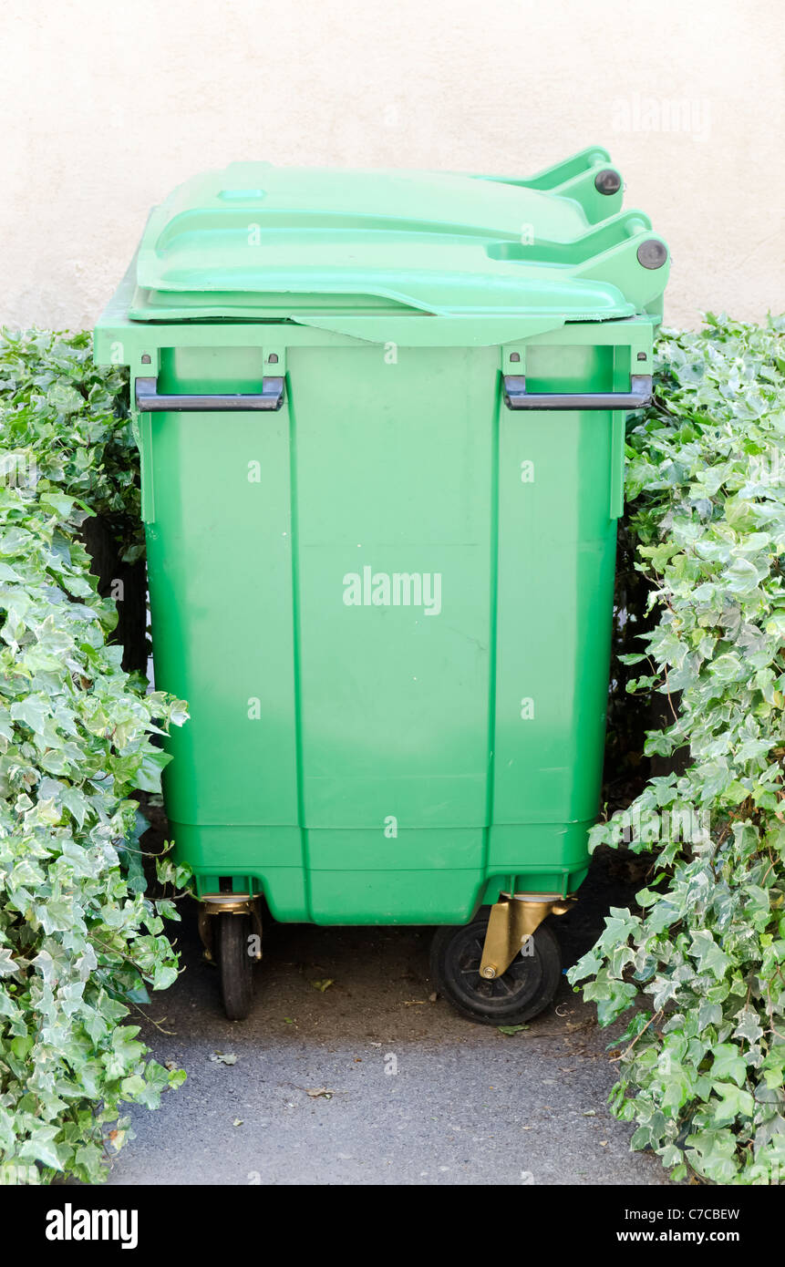 green garbage container between two plants Stock Photo Alamy