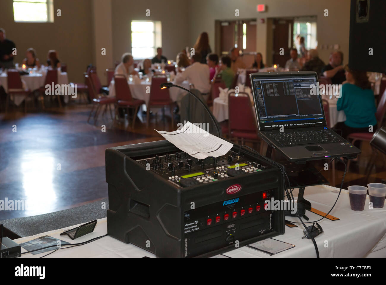 Disc jokey console,mixer and laptop set up during wedding reception ceremony with guests in the background Stock Photo