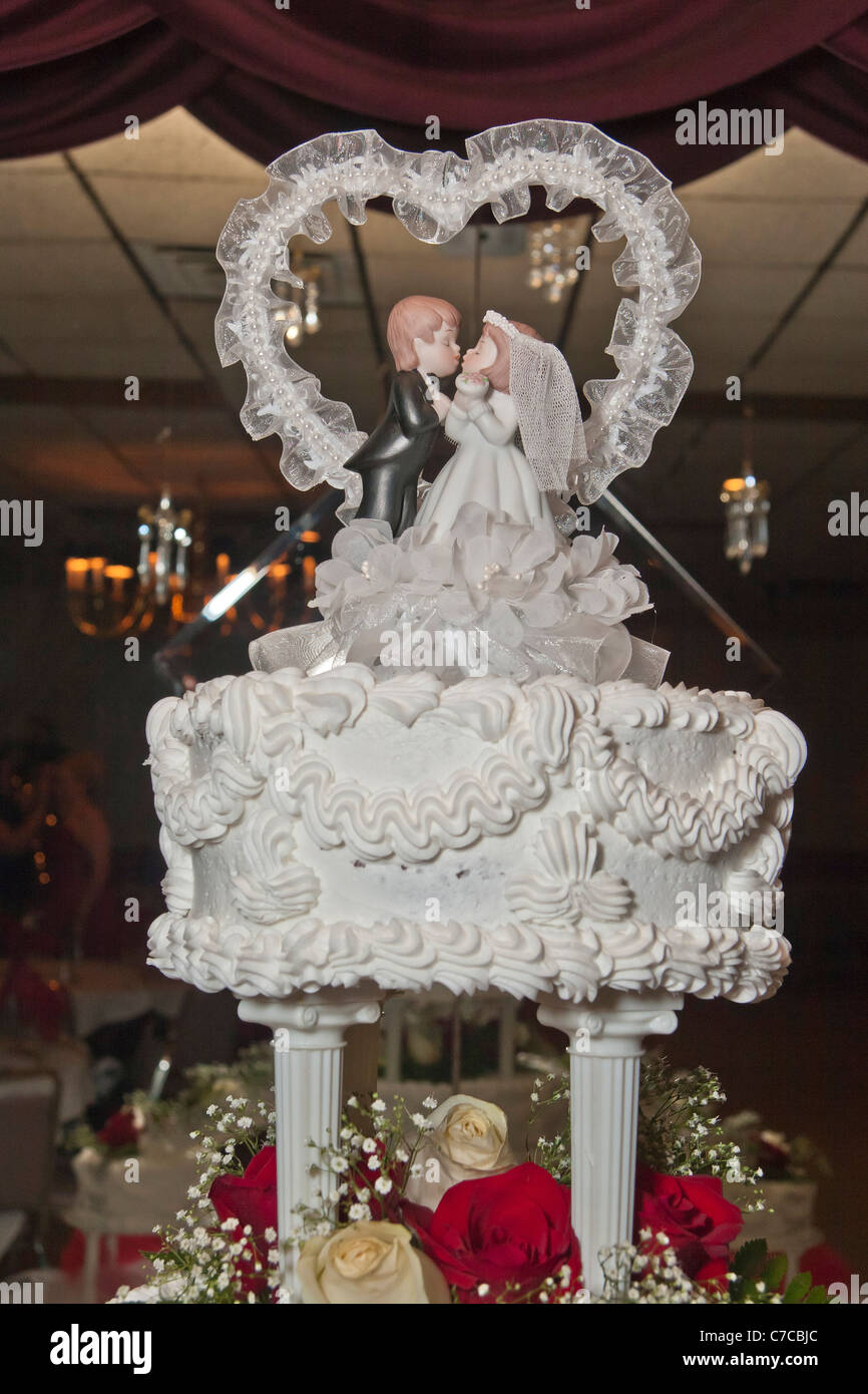 Decorative wedding cake topper bride and groom figurines kissing each other Stock Photo